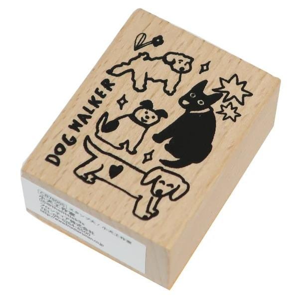 A wooden stamp featuring a dog walking with other dogs, including a black dog and a white dog.