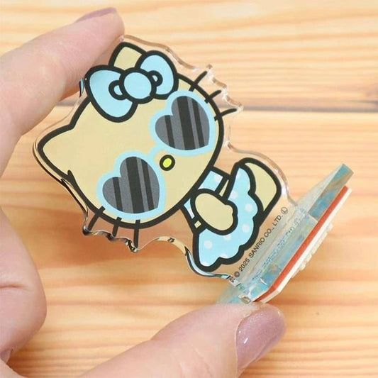 A hand holding a clear plastic figurine of a Hello Kitty character with heart-shaped sunglasses.