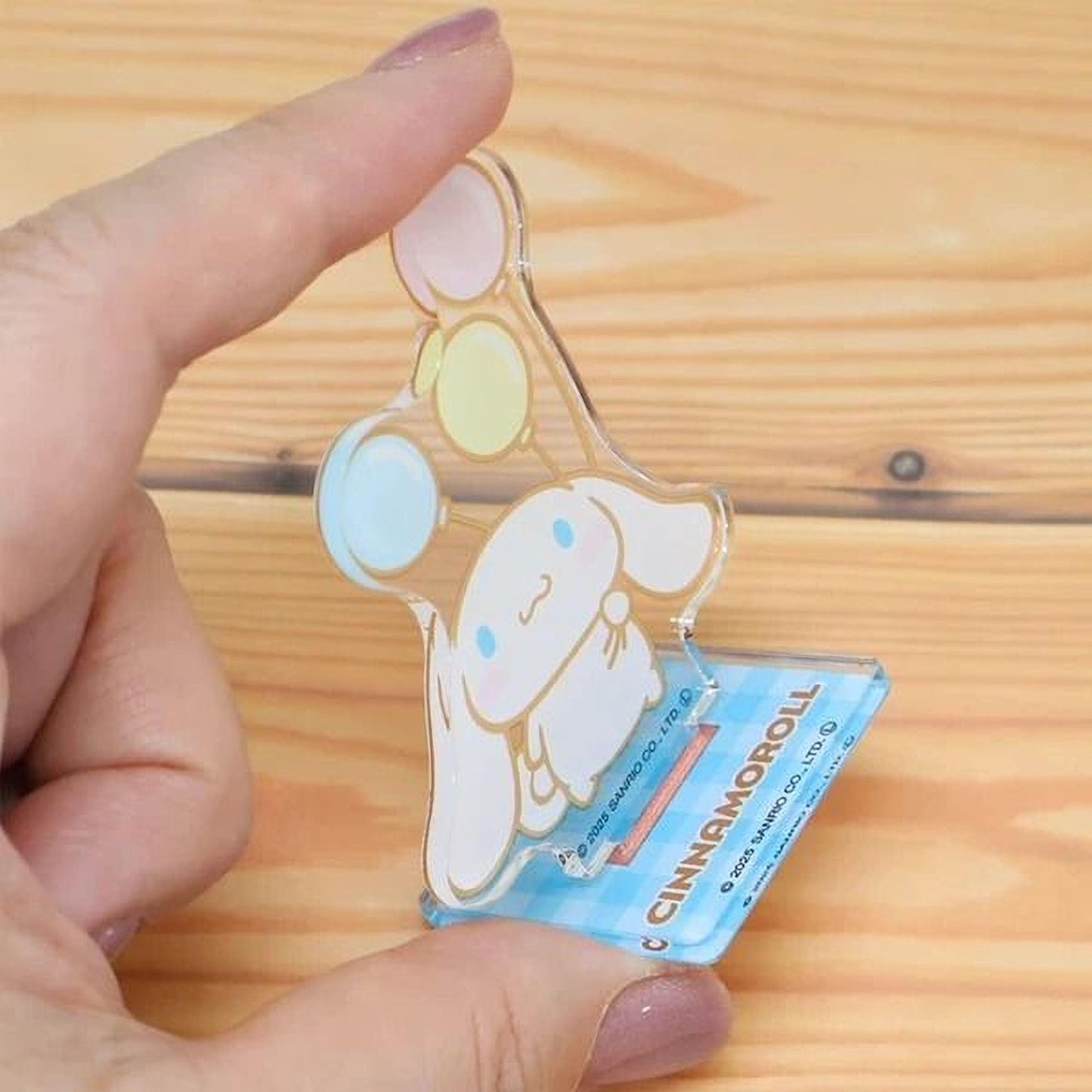 A hand is holding a small, clear plastic figurine of a cartoon character, which appears to be a cinnamon roll.