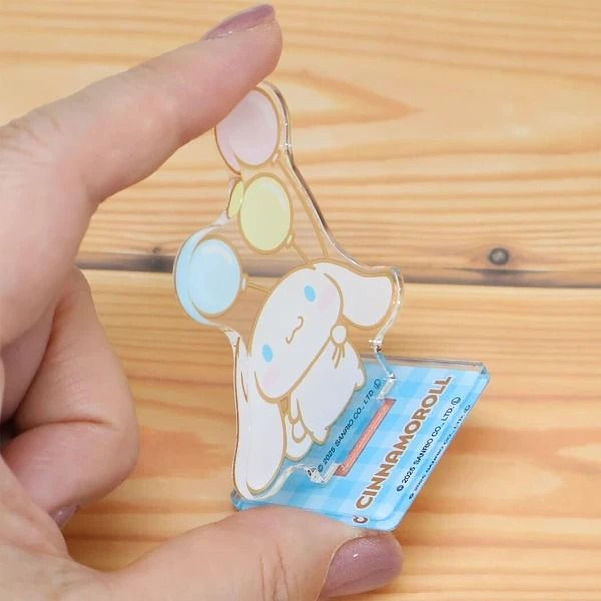 A hand is holding a small, clear plastic figurine of a cartoon character, which appears to be a cinnamon roll.