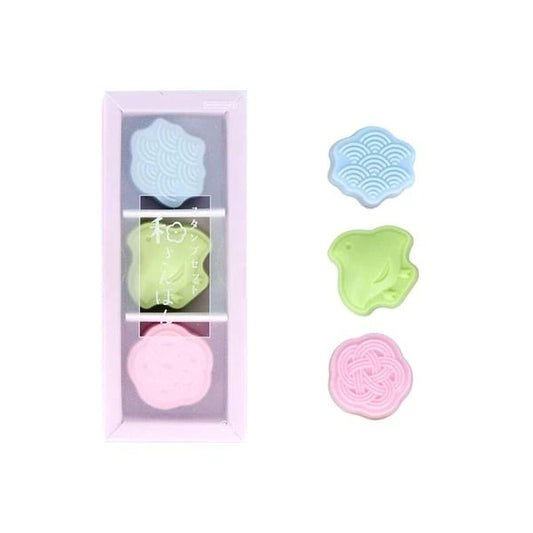 A pink box containing three colorful, round objects with different patterns, and a white background.