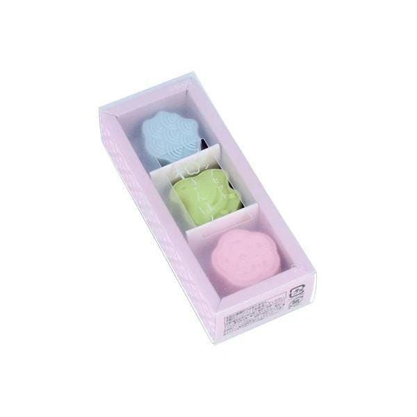 A pink box containing three small, colorful objects, possibly candies or sweets.