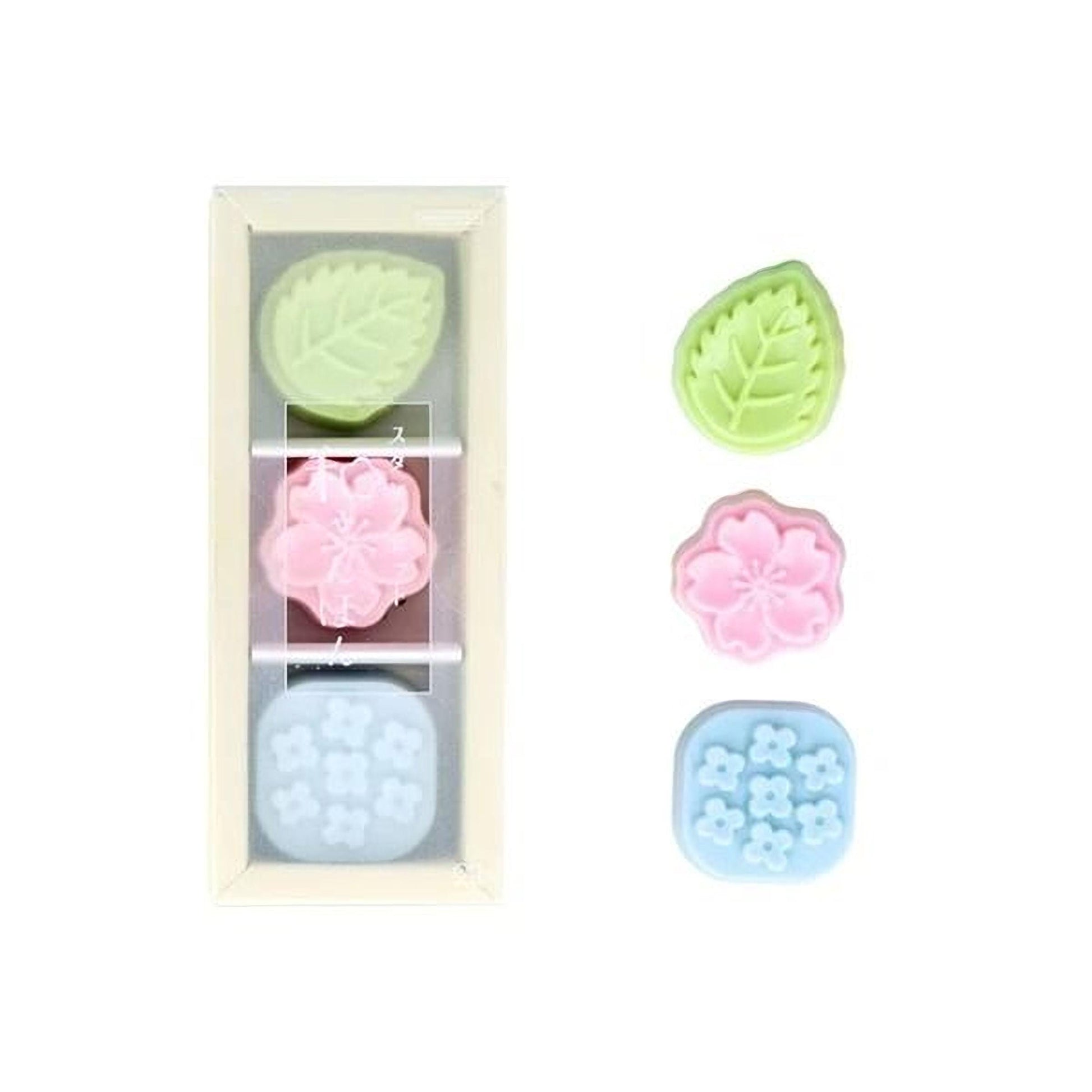 three colorful flower-shaped molds, each with a different color: green, pink, and blue.