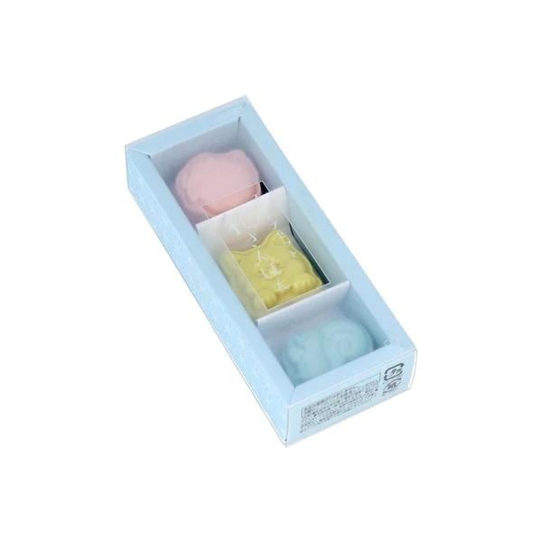 A light blue rectangular box containing three small, colorful objects, possibly a set of three small toys or decorative items.