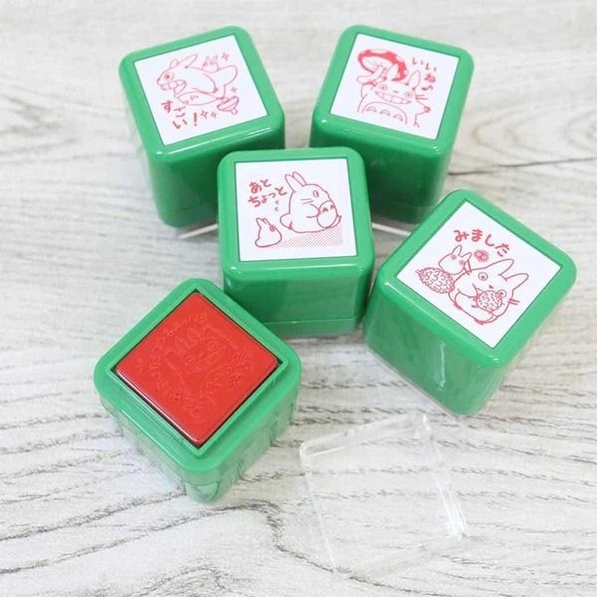 a collection of green and red stamp-like objects, each with a unique design and illustration, arranged on a wooden surface.