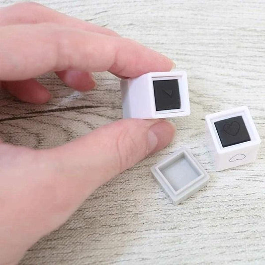 A hand is holding two small white and black objects, which appear to be some sort of decorative or functional items.