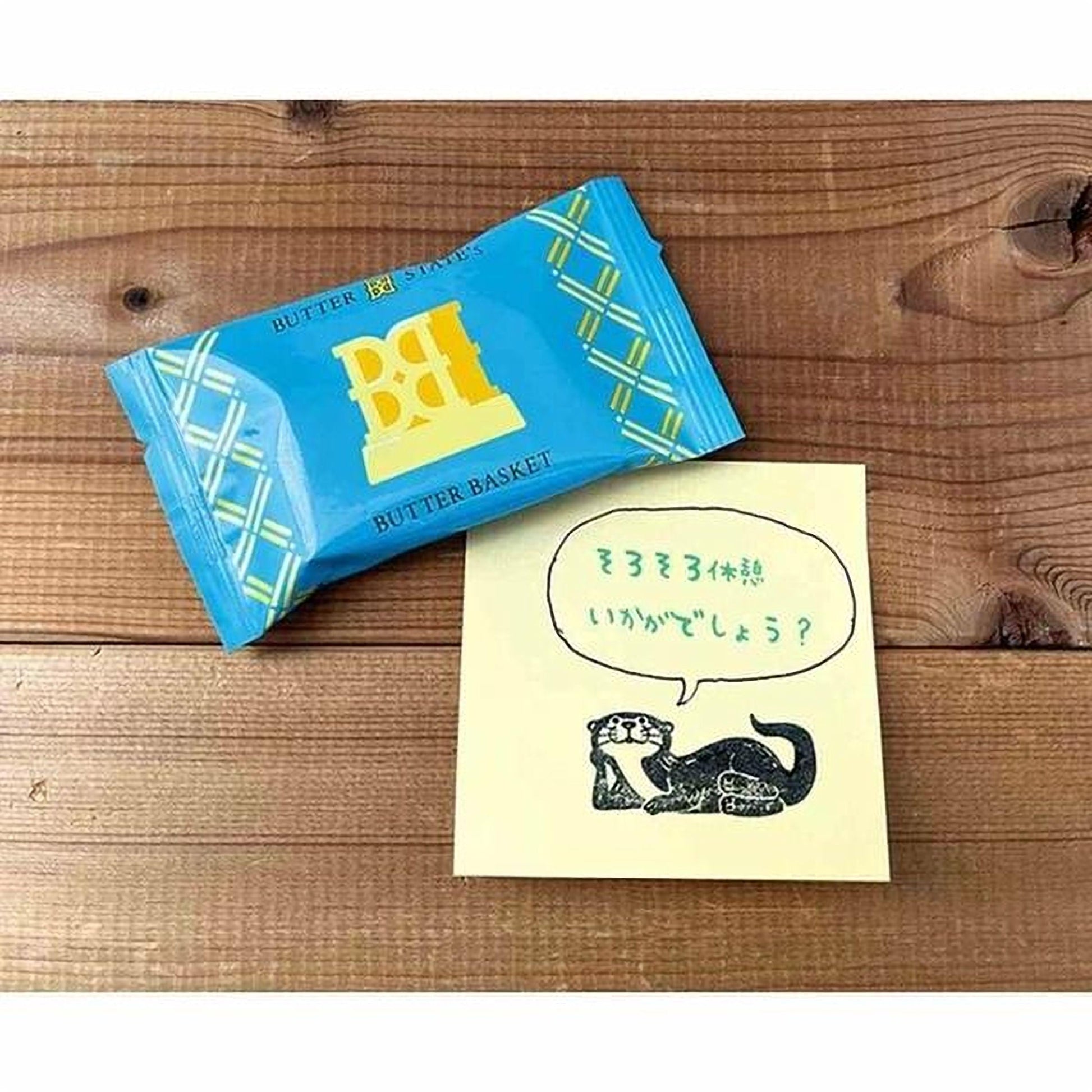 a blue package of Butter Basket and a yellow sticky note with a drawing of an otter and some Japanese text.