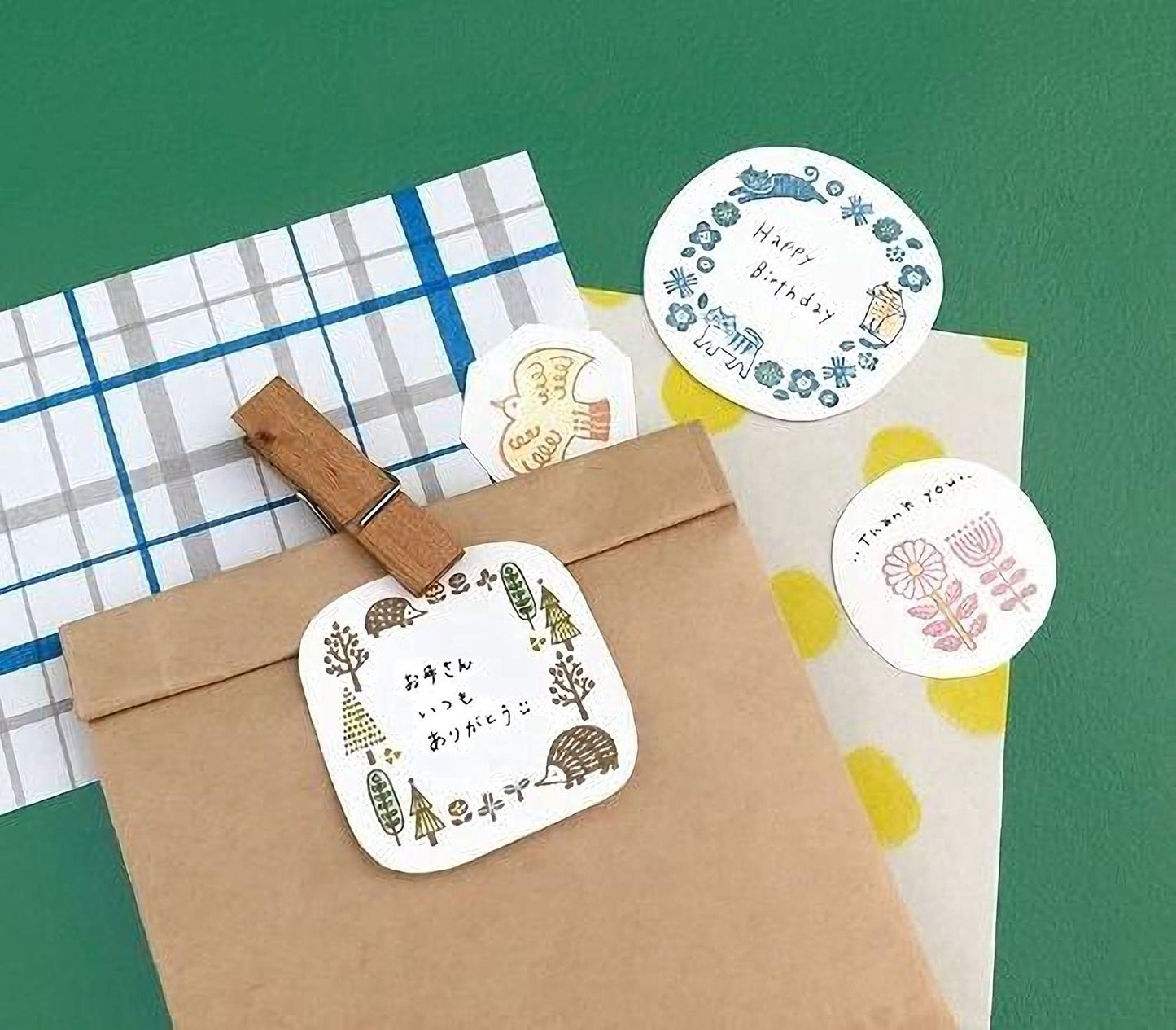 a brown paper bag with a wooden clothespin attached to it, along with various other items such as a white paper with a blue border, a white paper with a floral design, and a white paper with a pink flower design.