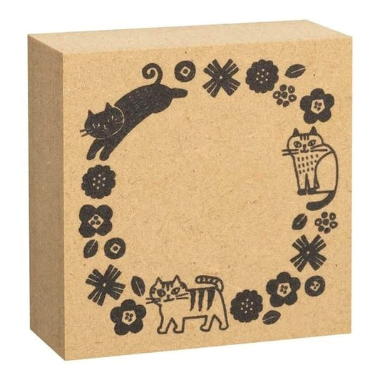 A square cardboard box with a decorative border featuring black cat illustrations and floral designs.