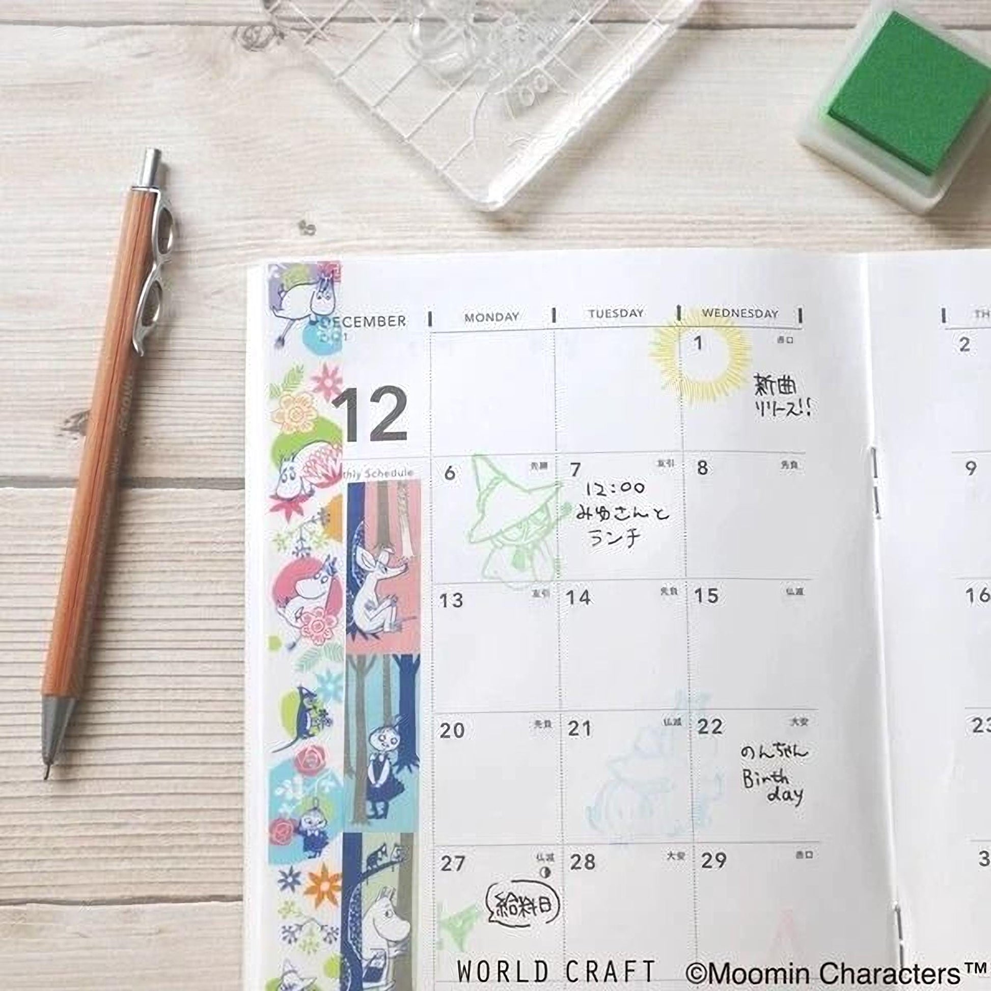 a calendar with colorful stickers and a pen on a wooden surface.