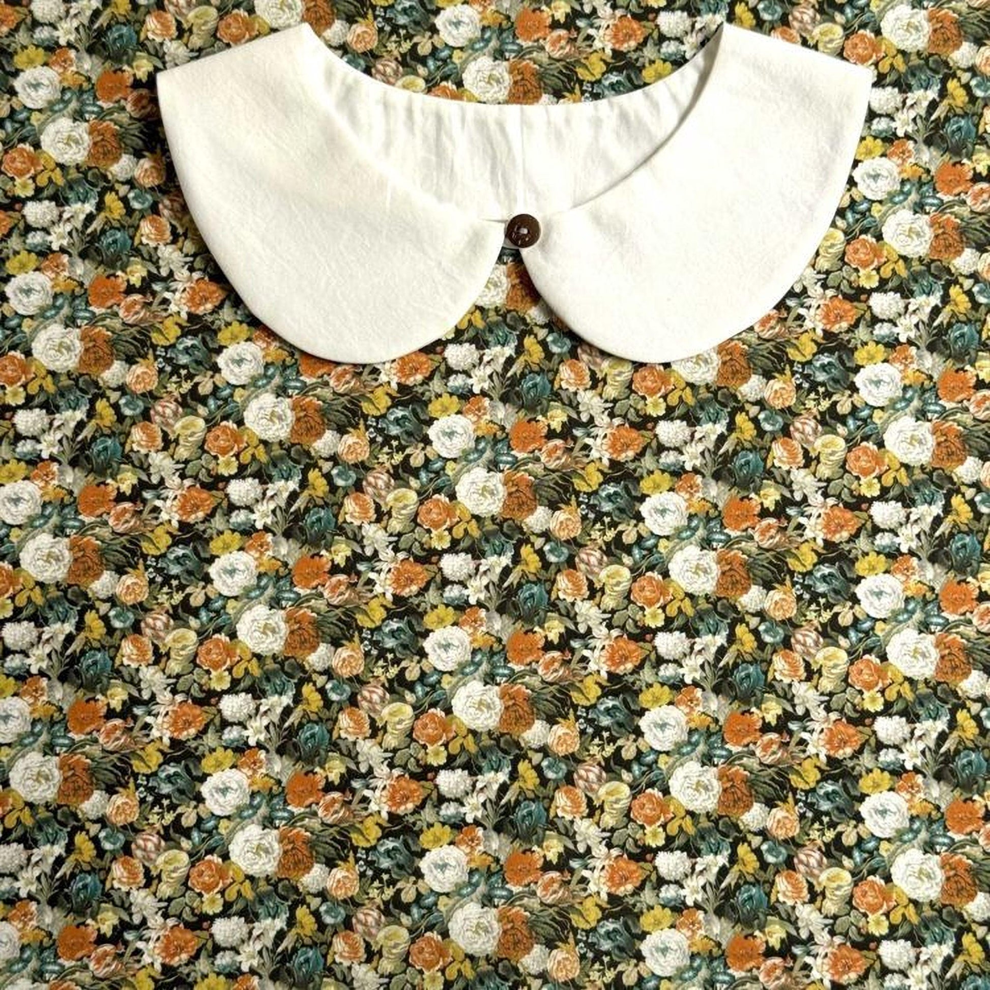 a white collar with a button, set against a background of a colorful floral print.