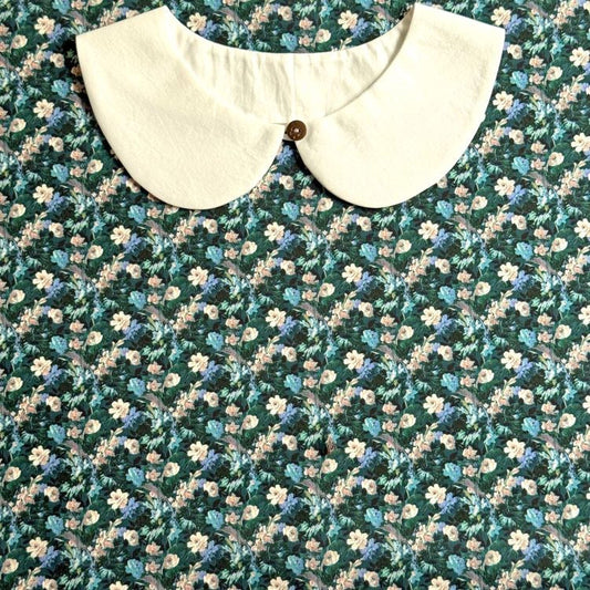 a white collar with a button, set against a background with a floral pattern.