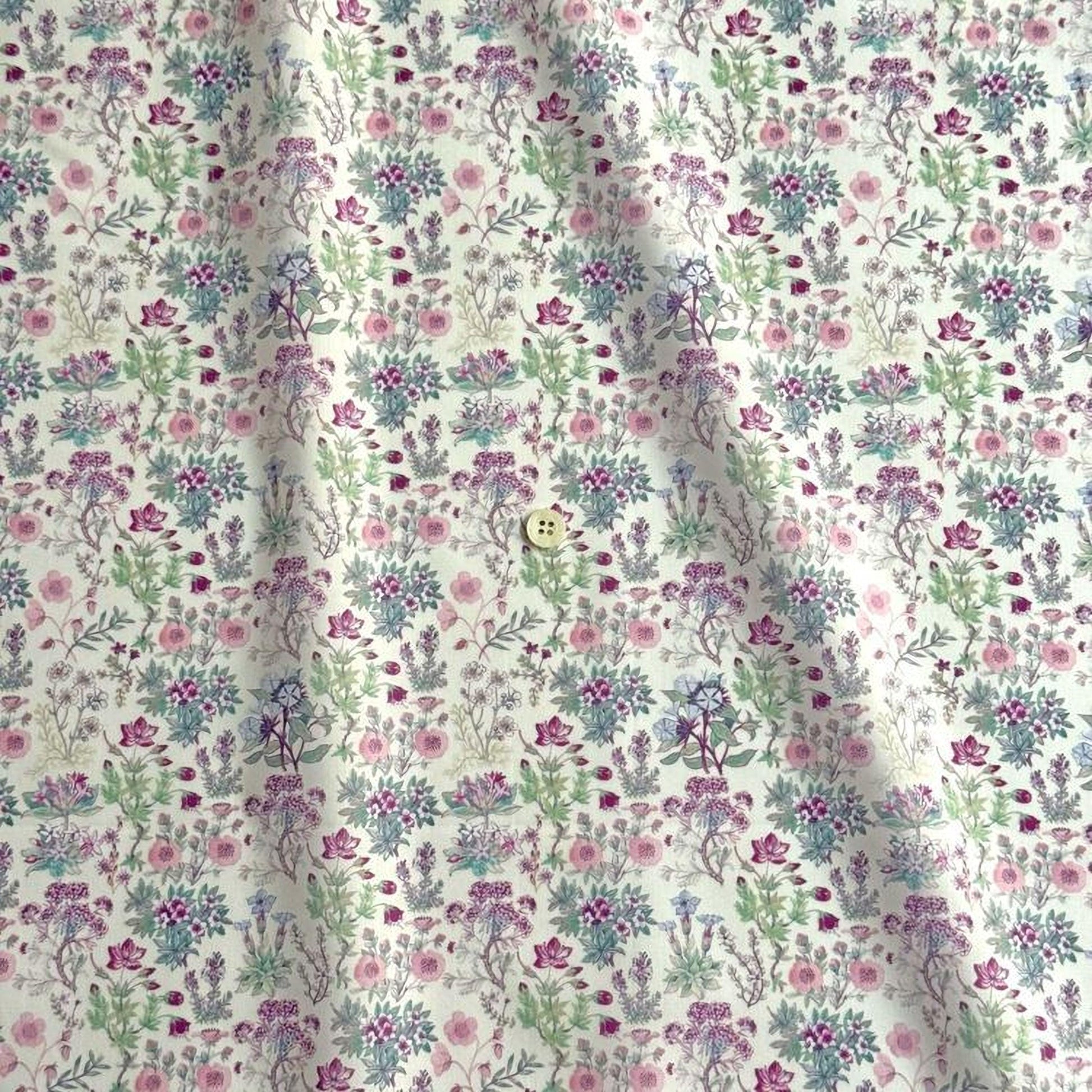 a fabric with a repeating floral pattern in shades of pink, green, and white. The pattern consists of various flowers and leaves, creating a visually appealing and intricate design.