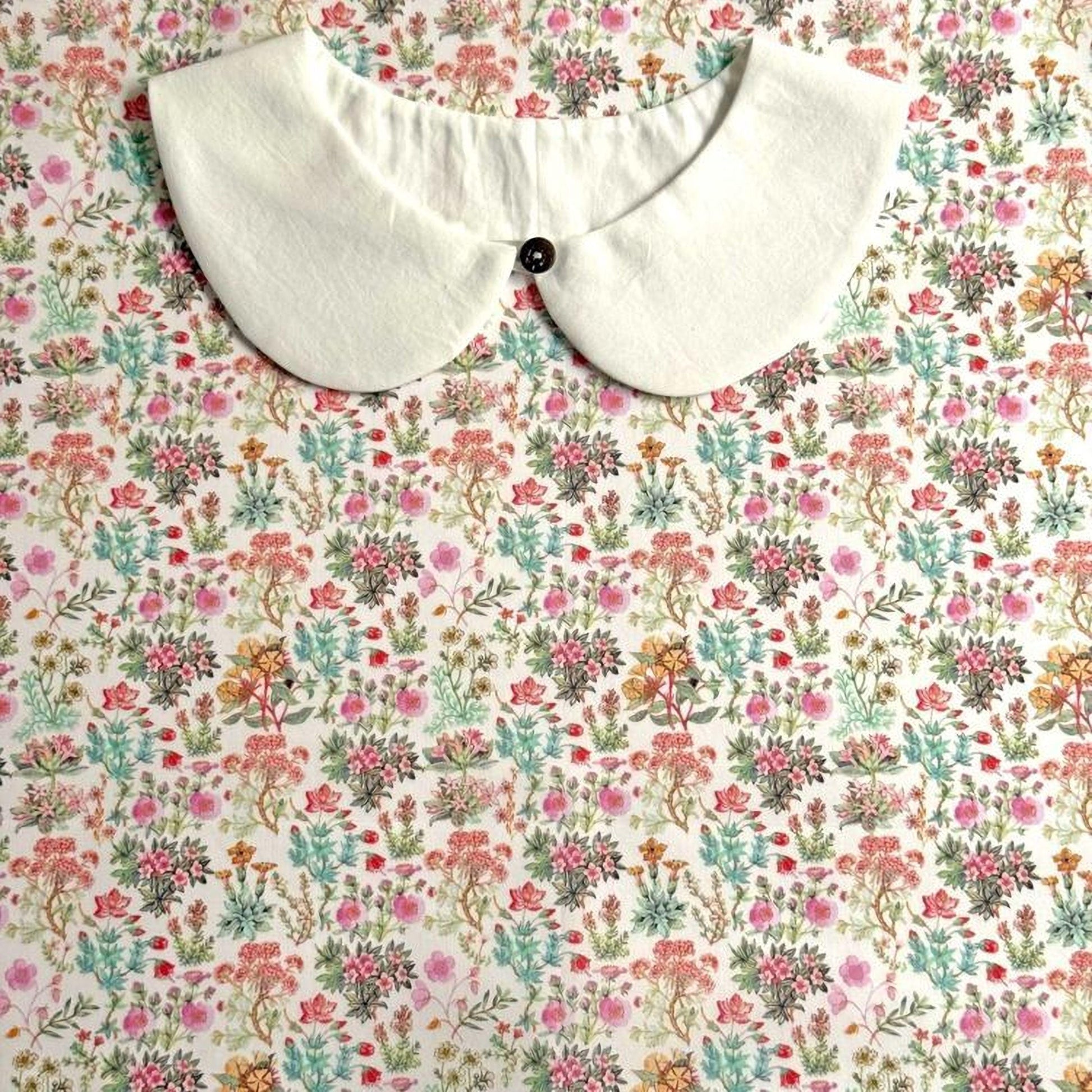 a white collar with a button, set against a background with a floral print.