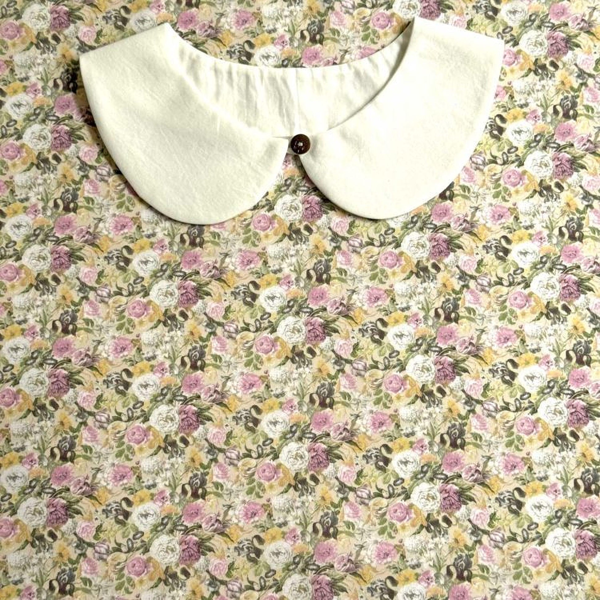 a white collar with a button, set against a background of a floral print fabric.