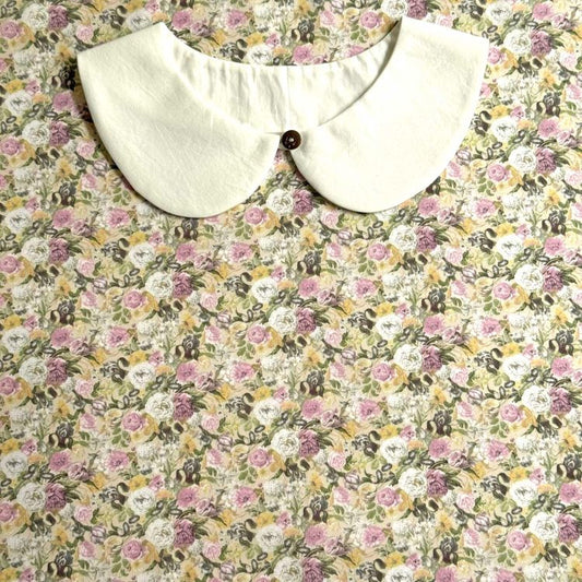 a white collar with a button, set against a background of a floral print fabric.
