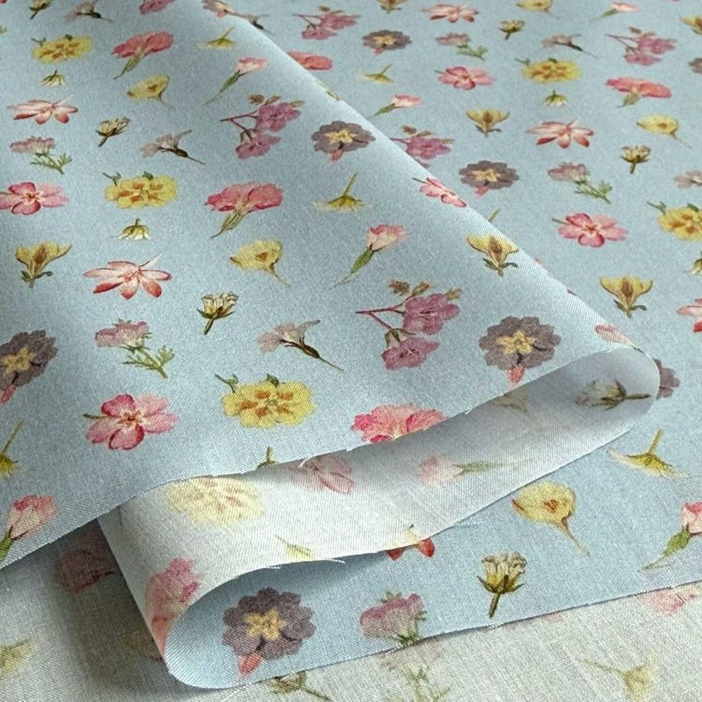 a close-up view of a fabric with a repeating floral pattern in various colors, including pink, yellow, and purple.