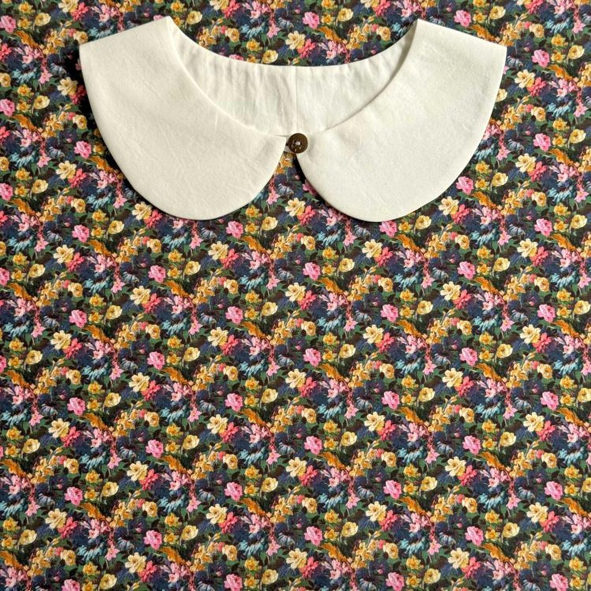 a white collar with a button, set against a colorful floral print background.