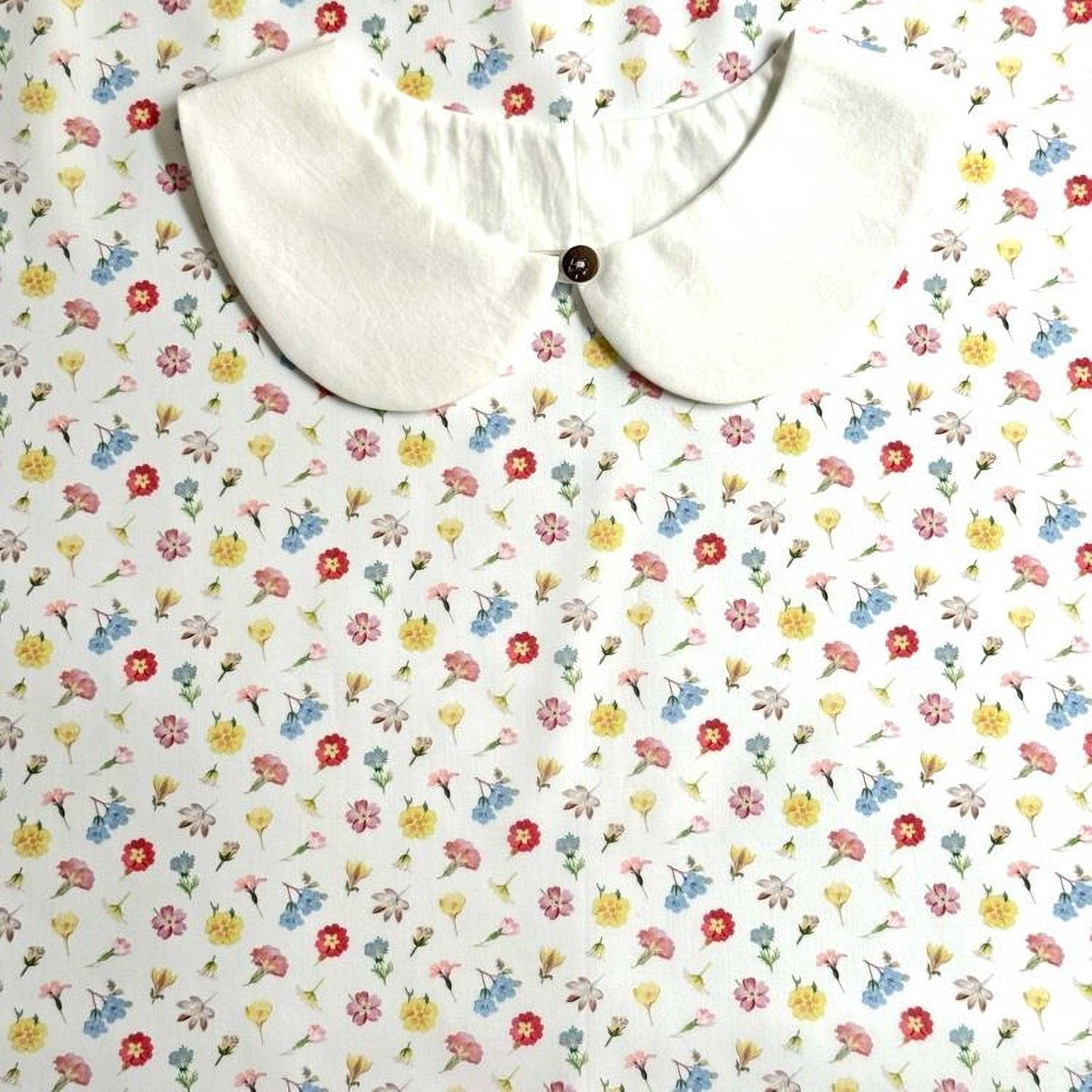a white collar with a button, set against a background with a floral print.