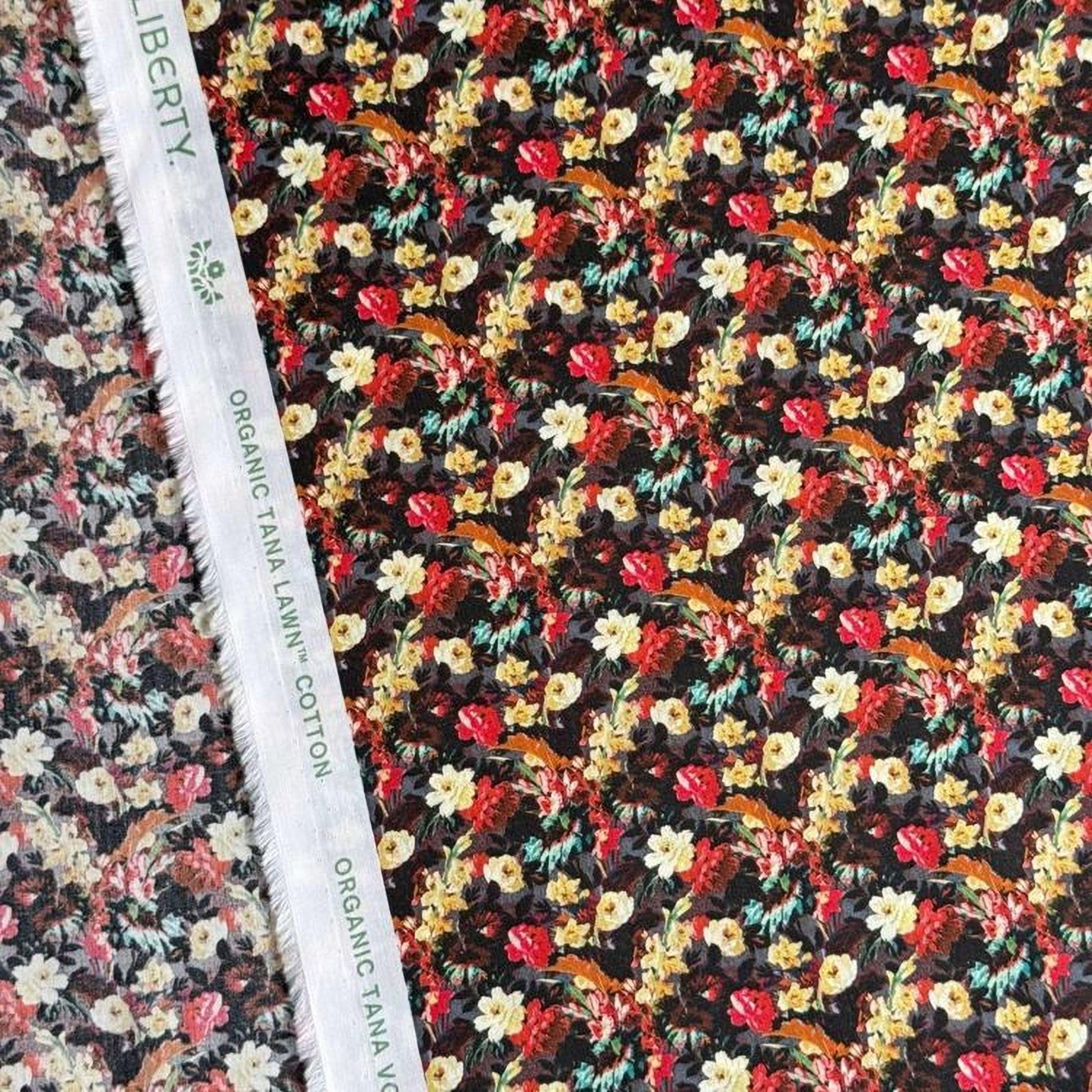a close-up view of a fabric with a floral pattern, featuring a variety of colorful flowers and leaves. The fabric appears to be made of cotton and is displayed on a white fabric ruler.
