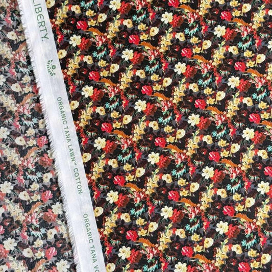 a close-up view of a fabric with a floral pattern, featuring a variety of colorful flowers and leaves. The fabric appears to be made of cotton and is displayed on a white fabric ruler.