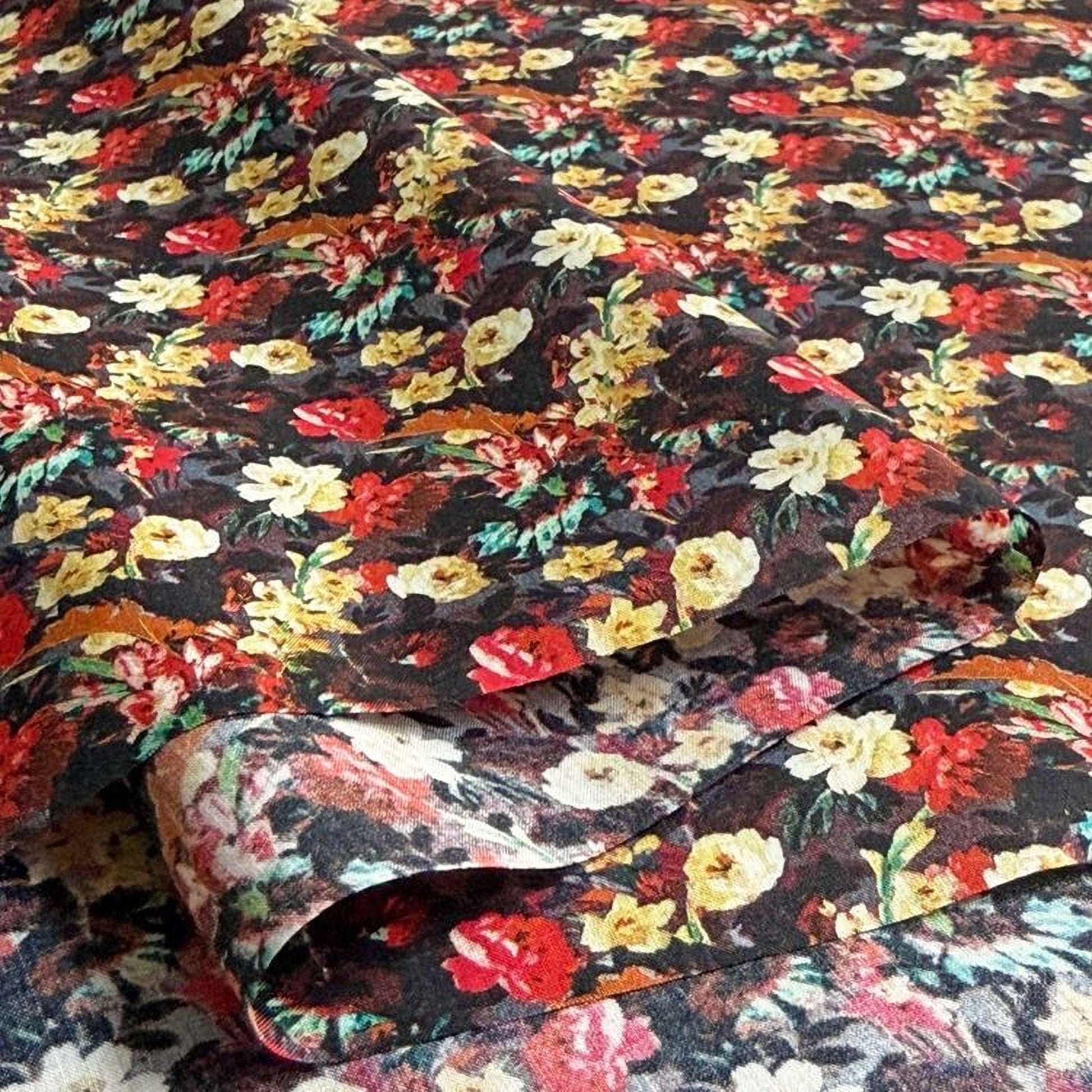a close-up view of a fabric with a vibrant floral pattern. The fabric appears to be a dark-colored material with a repeating pattern of red, yellow, and white flowers. The pattern is intricate and detailed, creating a visually striking and eye-catching design.