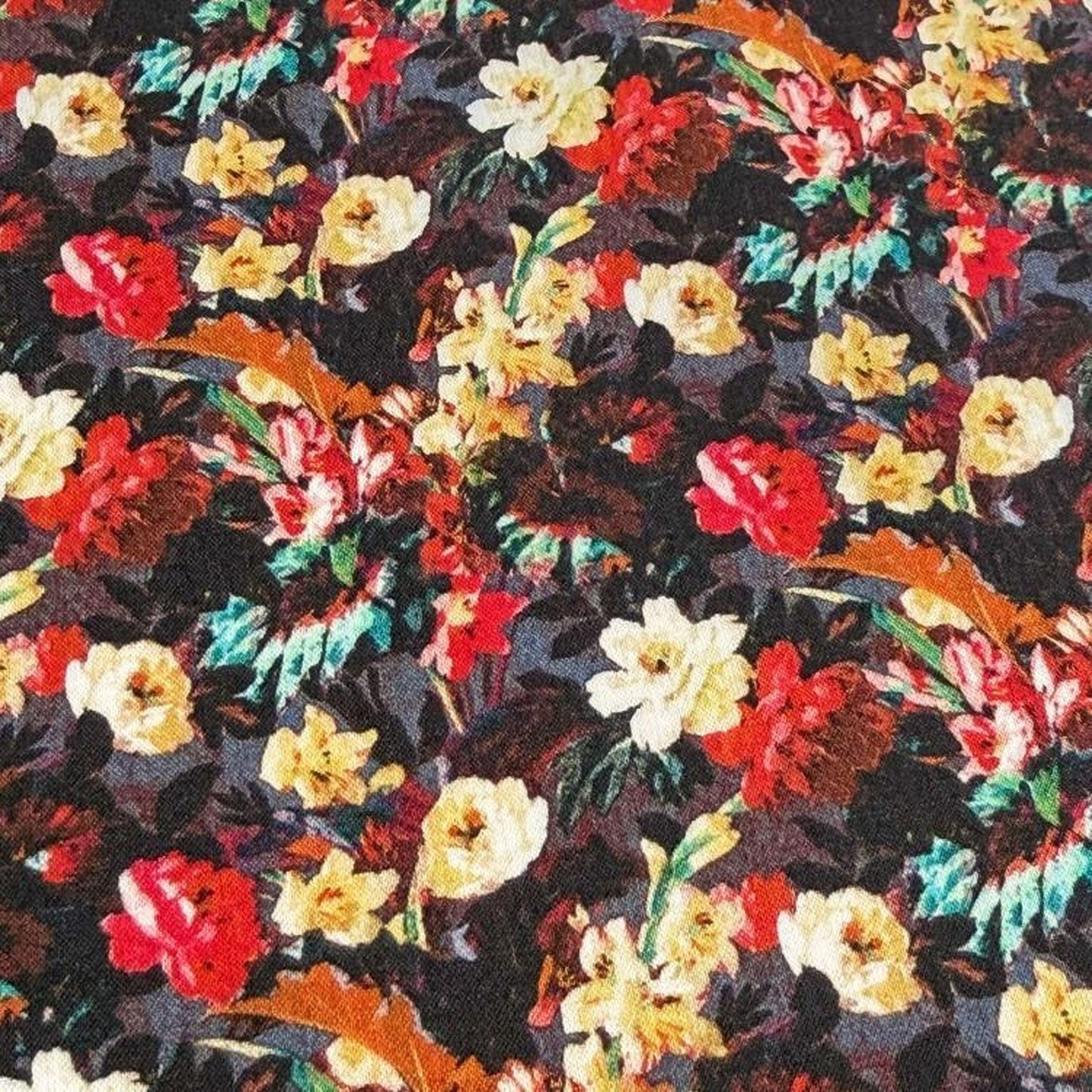 The image is a close-up of a fabric with a vibrant floral pattern, featuring a variety of colorful flowers in shades of red, yellow, and white.