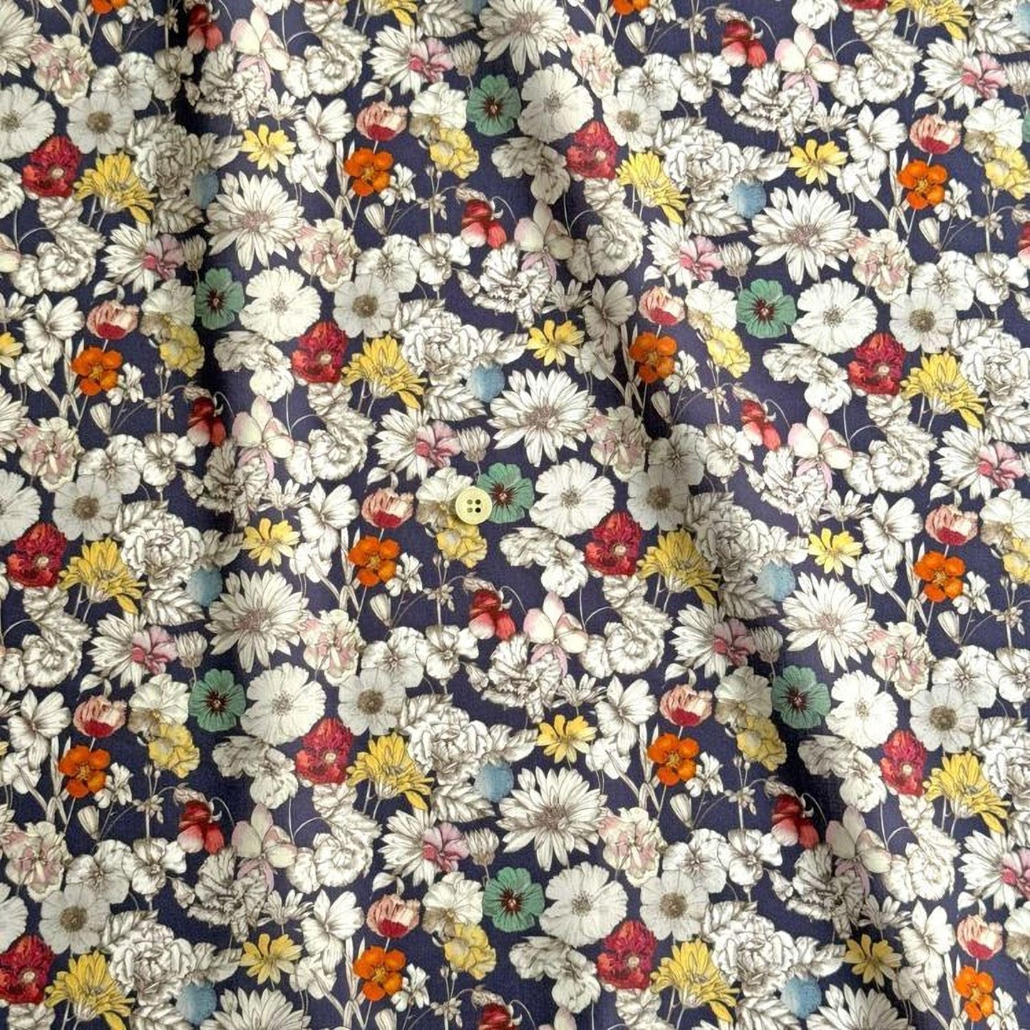 The image is a close-up view of a fabric with a floral pattern, featuring a variety of colorful flowers in shades of white, yellow, orange, and red. The flowers are arranged in a repeating pattern, creating a visually appealing and vibrant design.
