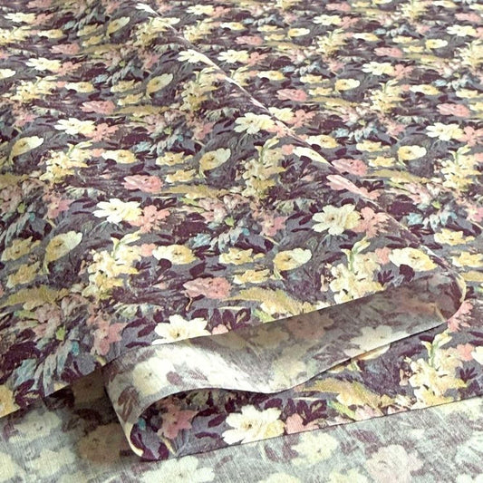 a close-up view of a fabric with a floral pattern, featuring a variety of colors including pink, yellow, and purple.