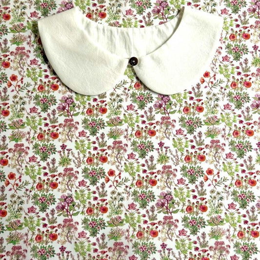 a white collar with a button, set against a background with a floral print.