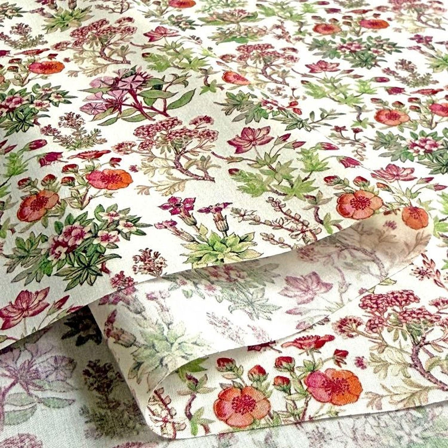 a close-up view of a fabric with a floral pattern, including various types of flowers and leaves in shades of red, green, and white.