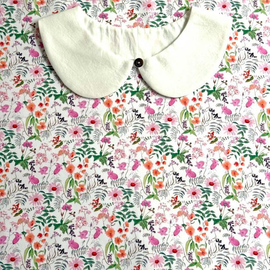 a white collar with a button, placed on a floral print fabric.