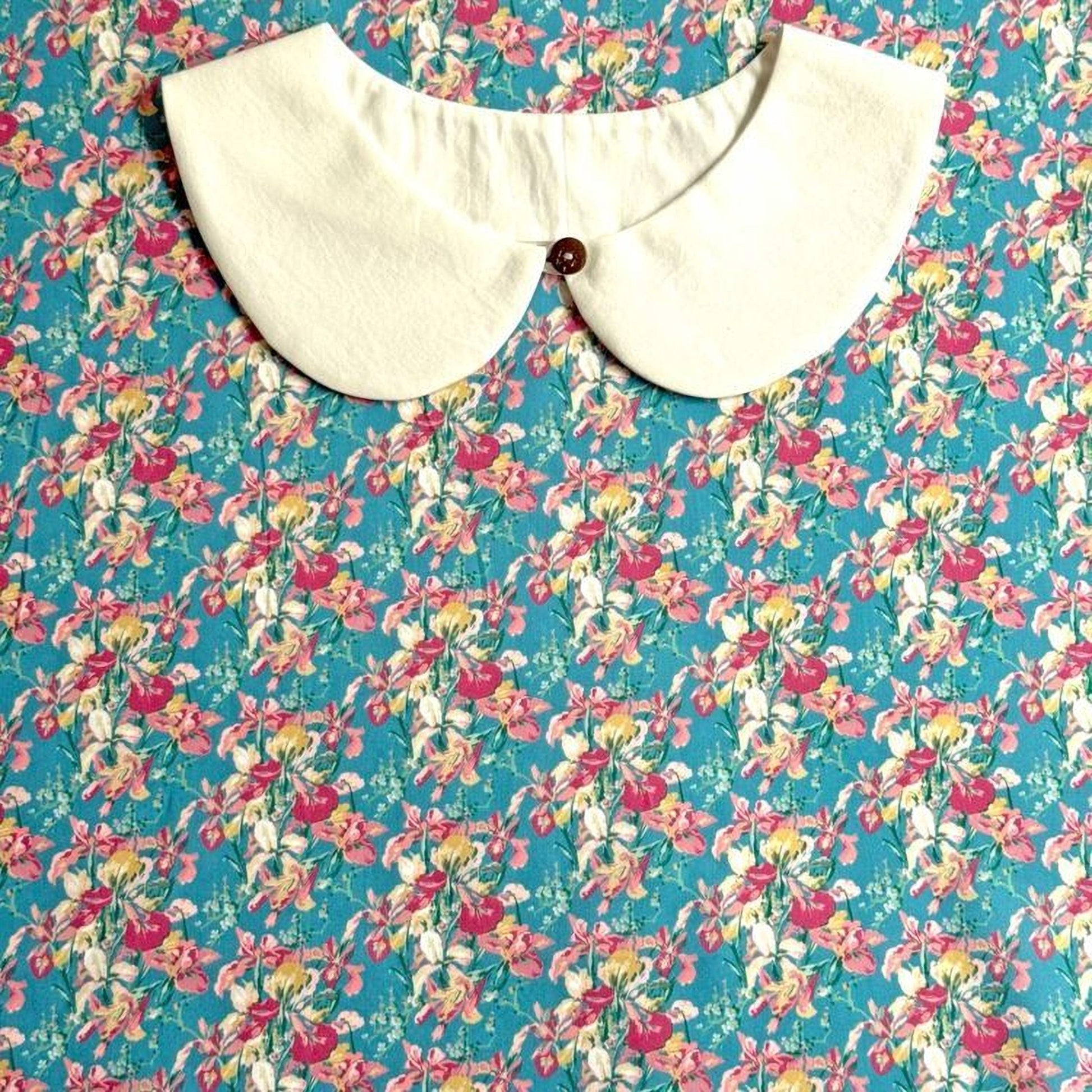 a white collar with a button, set against a background of a floral print fabric.