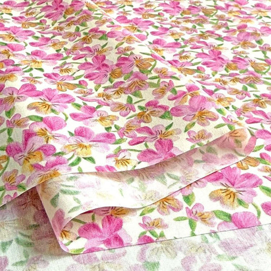 a close-up view of a fabric with a floral pattern, predominantly pink and yellow in color. The fabric appears to be folded or rolled, revealing the intricate design of the flowers.