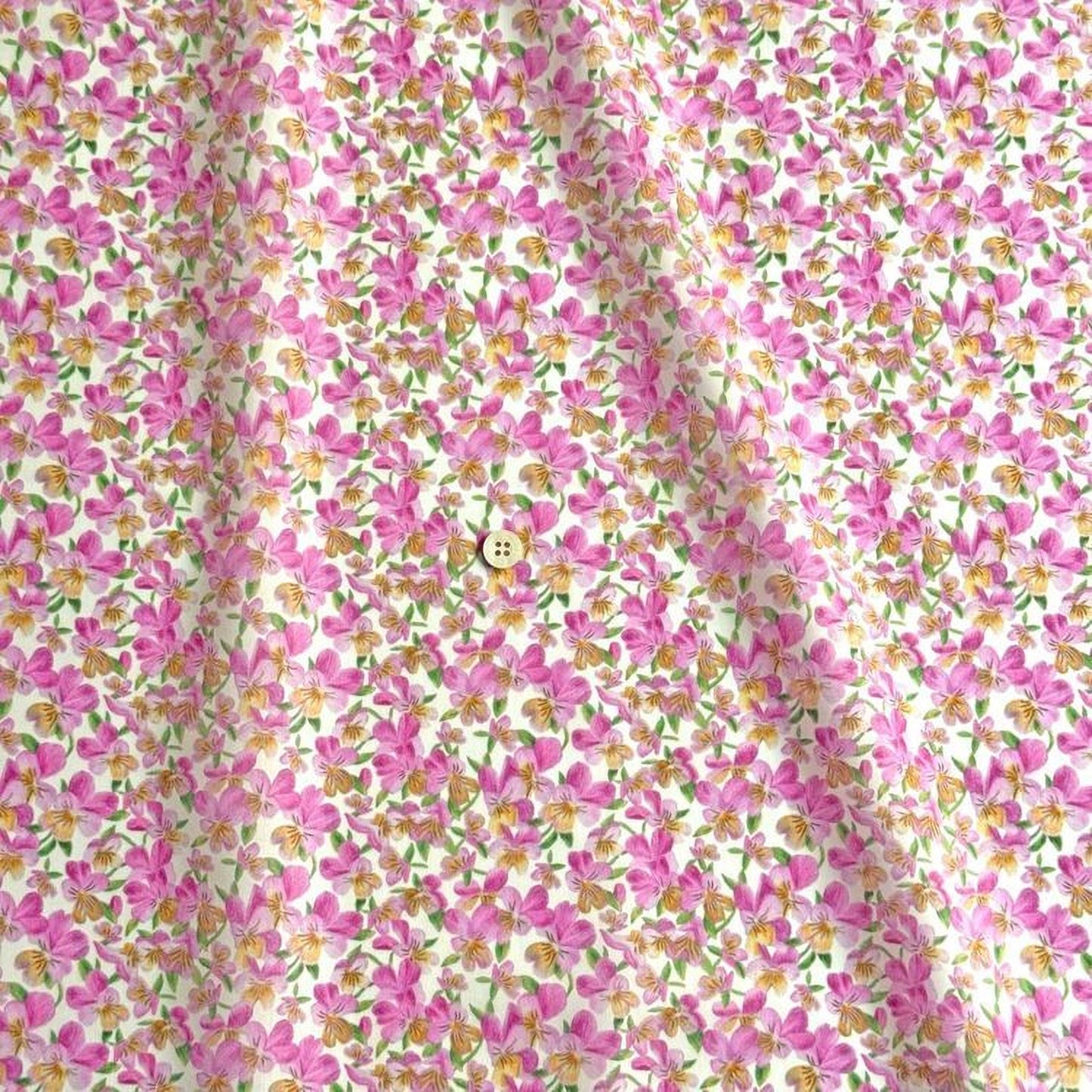 a close-up view of a fabric with a floral pattern in shades of pink and yellow. The fabric appears to be made of cotton and has a button visible in the center.