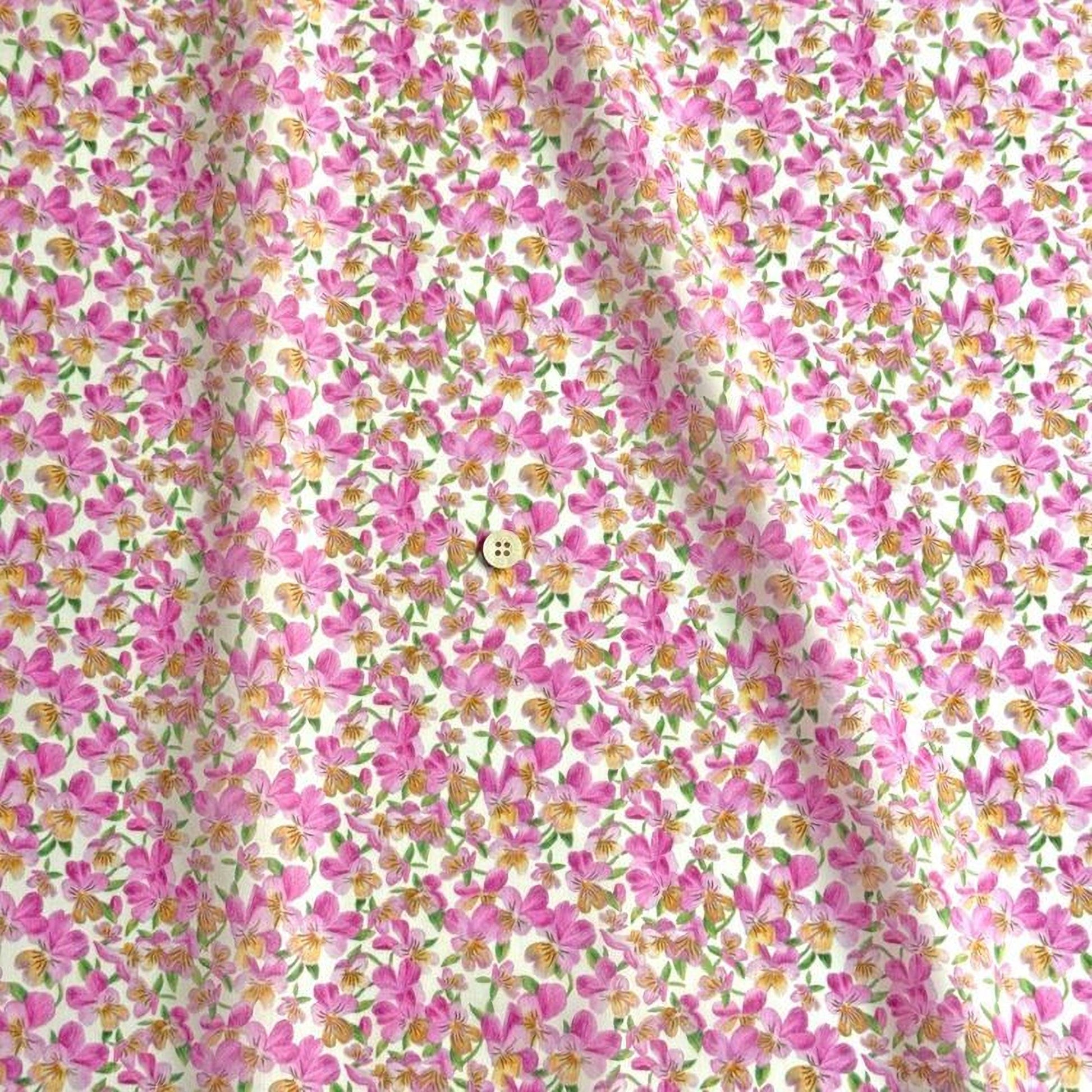 a close-up view of a fabric with a floral pattern in shades of pink and yellow. The fabric appears to be made of cotton and has a button visible in the center.