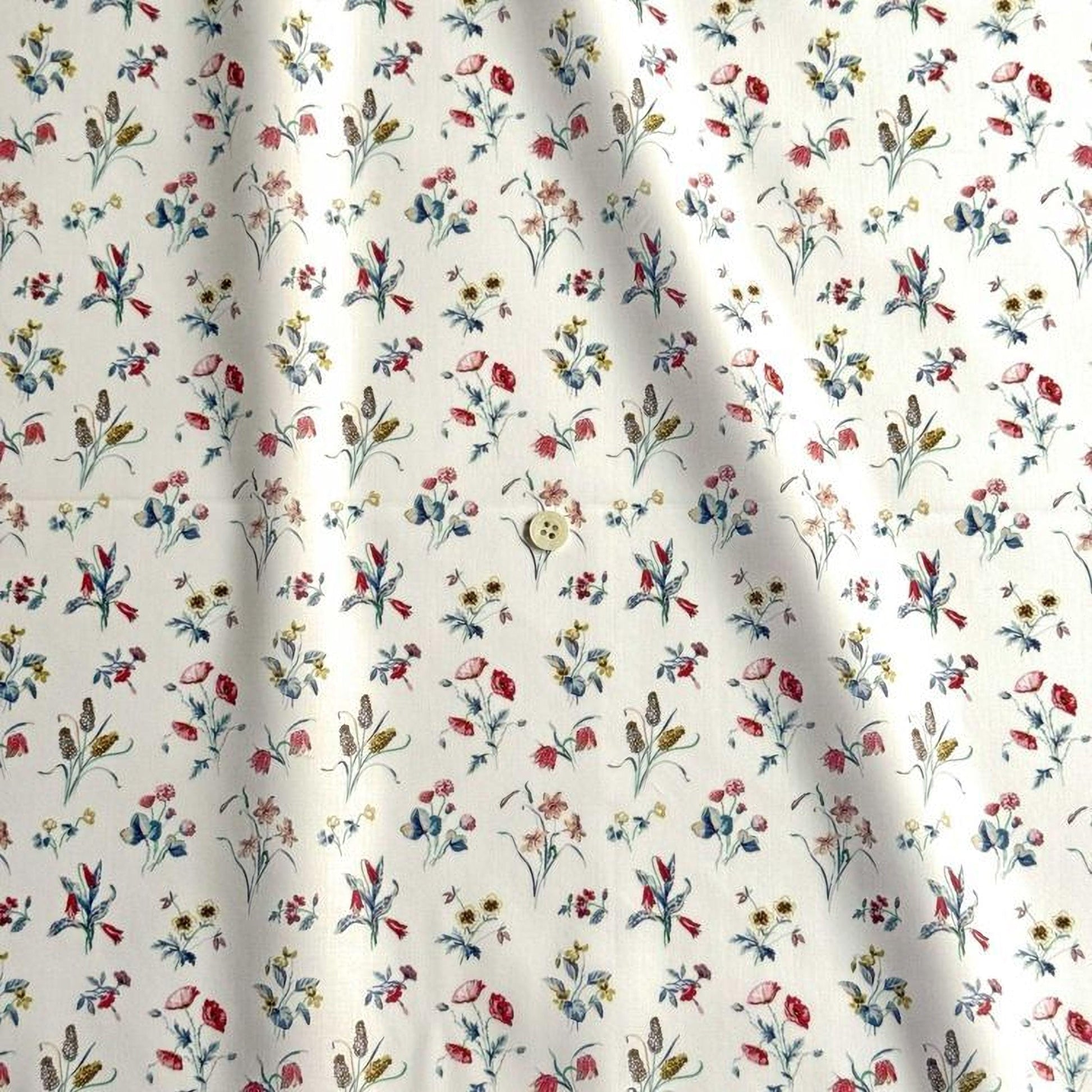 a close-up view of a fabric with a repeating floral pattern in various colors, including red, blue, yellow, and green. The pattern consists of small flowers and leaves, creating a visually appealing and intricate design.