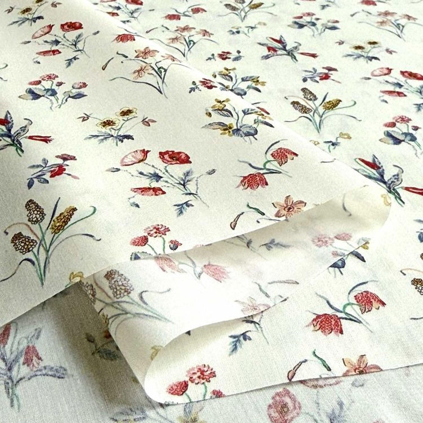 a close-up view of a fabric with a floral pattern, featuring various types of flowers and leaves in different colors and sizes.