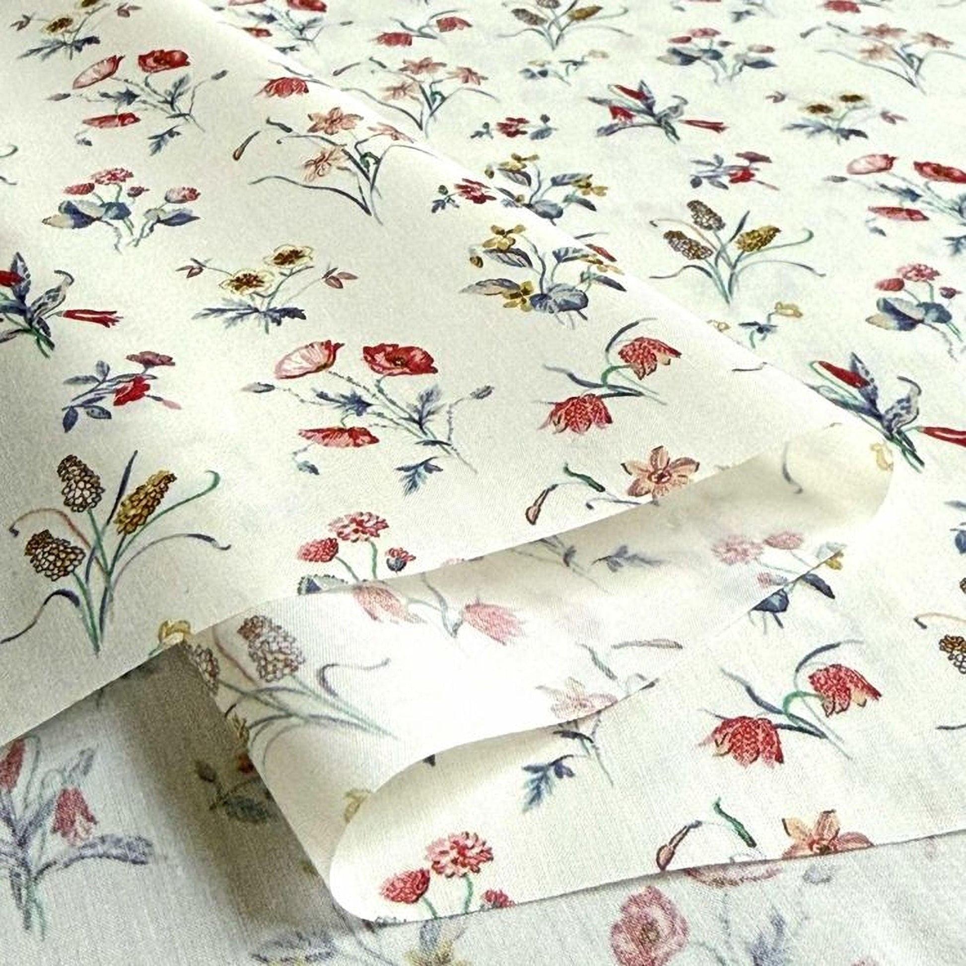 a close-up view of a fabric with a floral pattern, featuring various types of flowers and leaves in different colors and sizes.