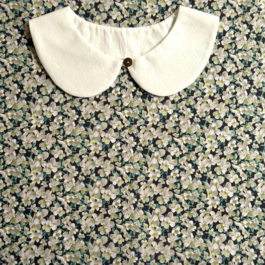 a white collar with a button, set against a background of a floral print fabric.