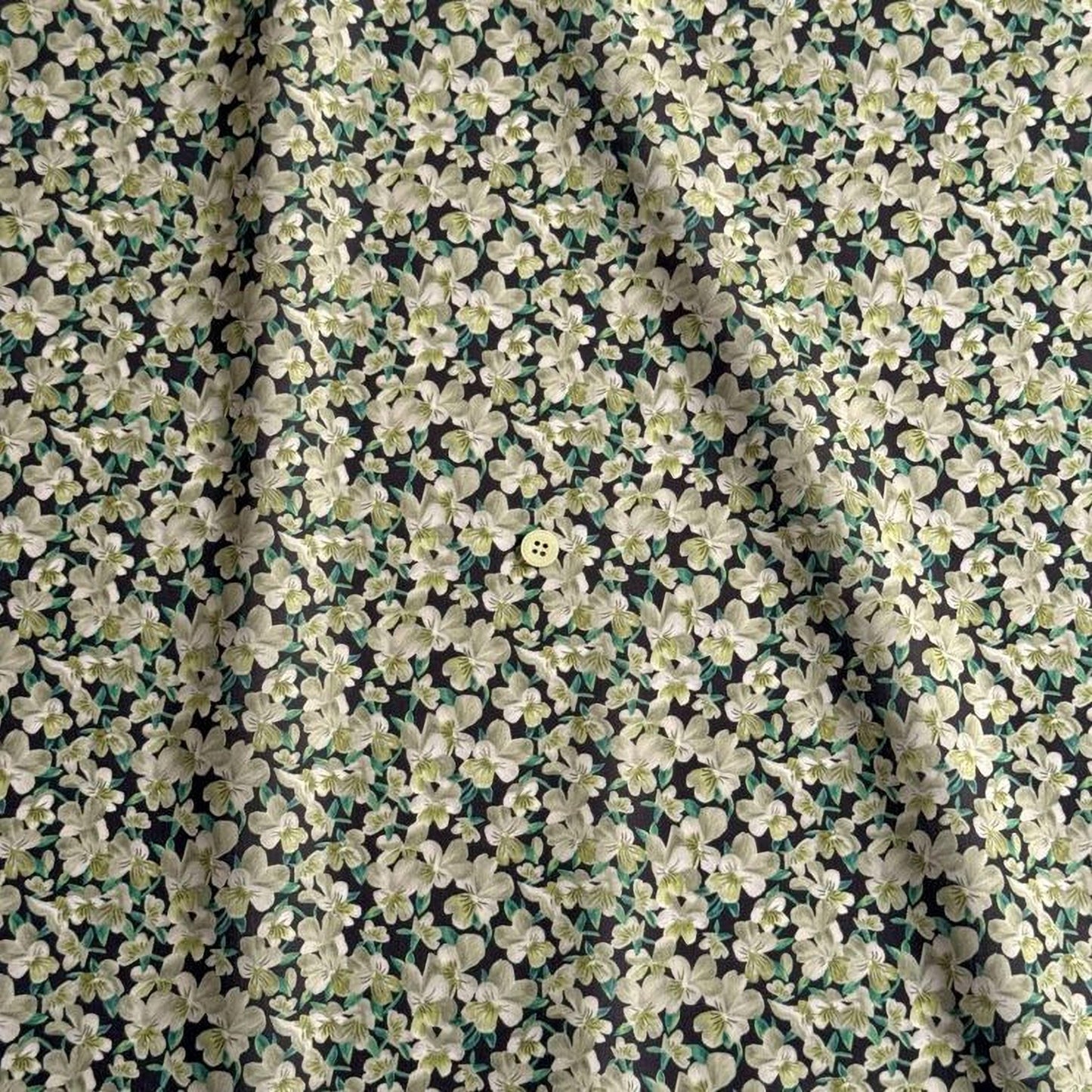 a close-up view of a fabric with a floral pattern, featuring a small button in the center.