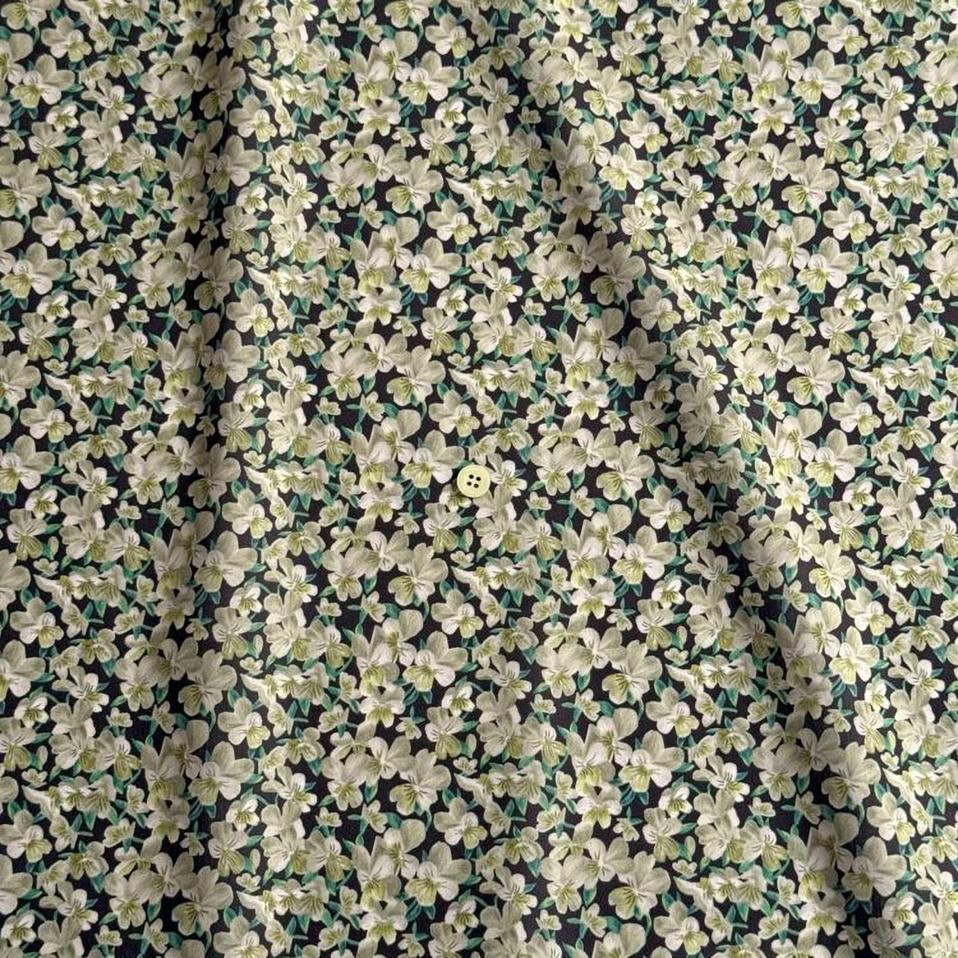 a close-up view of a fabric with a floral pattern, featuring a small button in the center.
