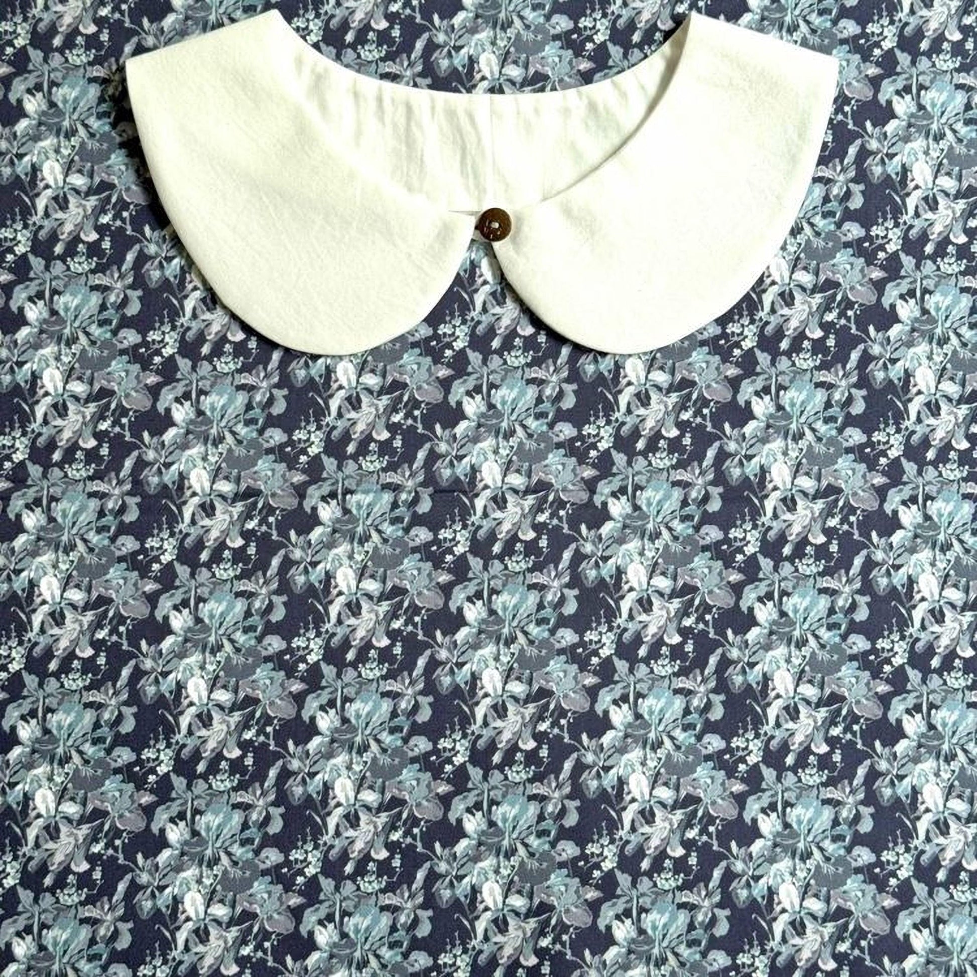 a white collar with a button, set against a background with a blue and white floral pattern.