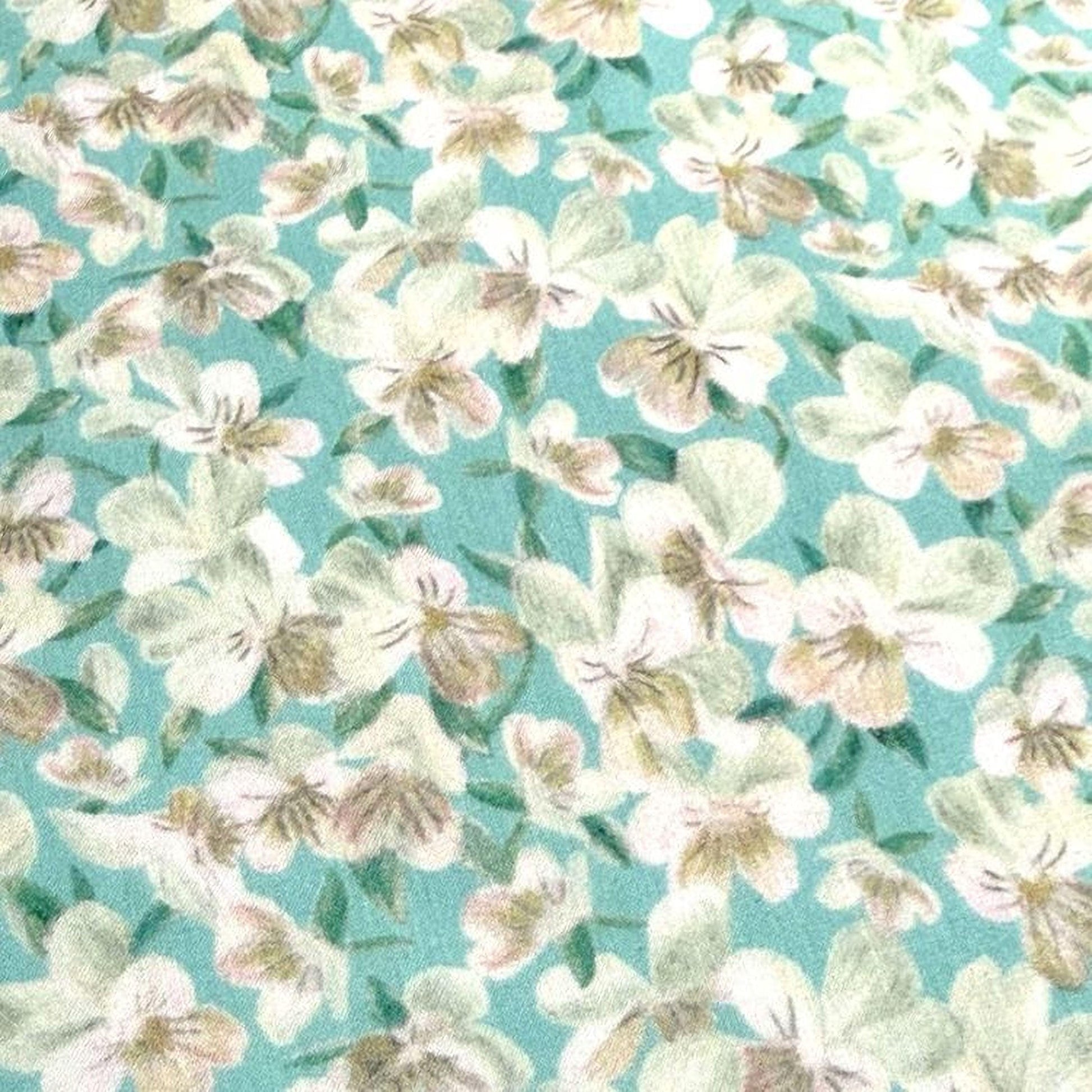 The image is a close-up of a fabric with a floral pattern, featuring white and green flowers against a turquoise background.
