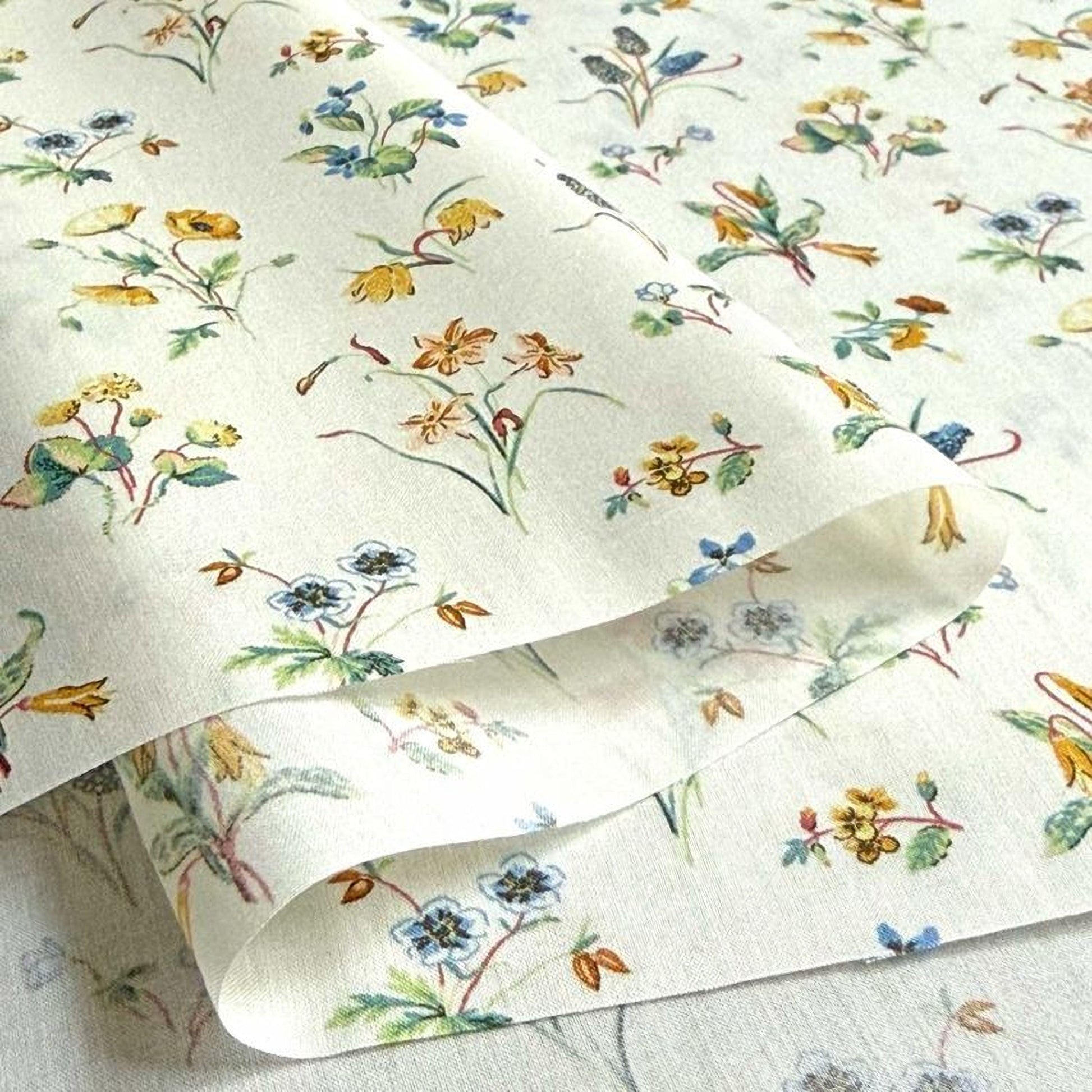 a close-up view of a fabric with a floral pattern, featuring various types of flowers and leaves in different colors.