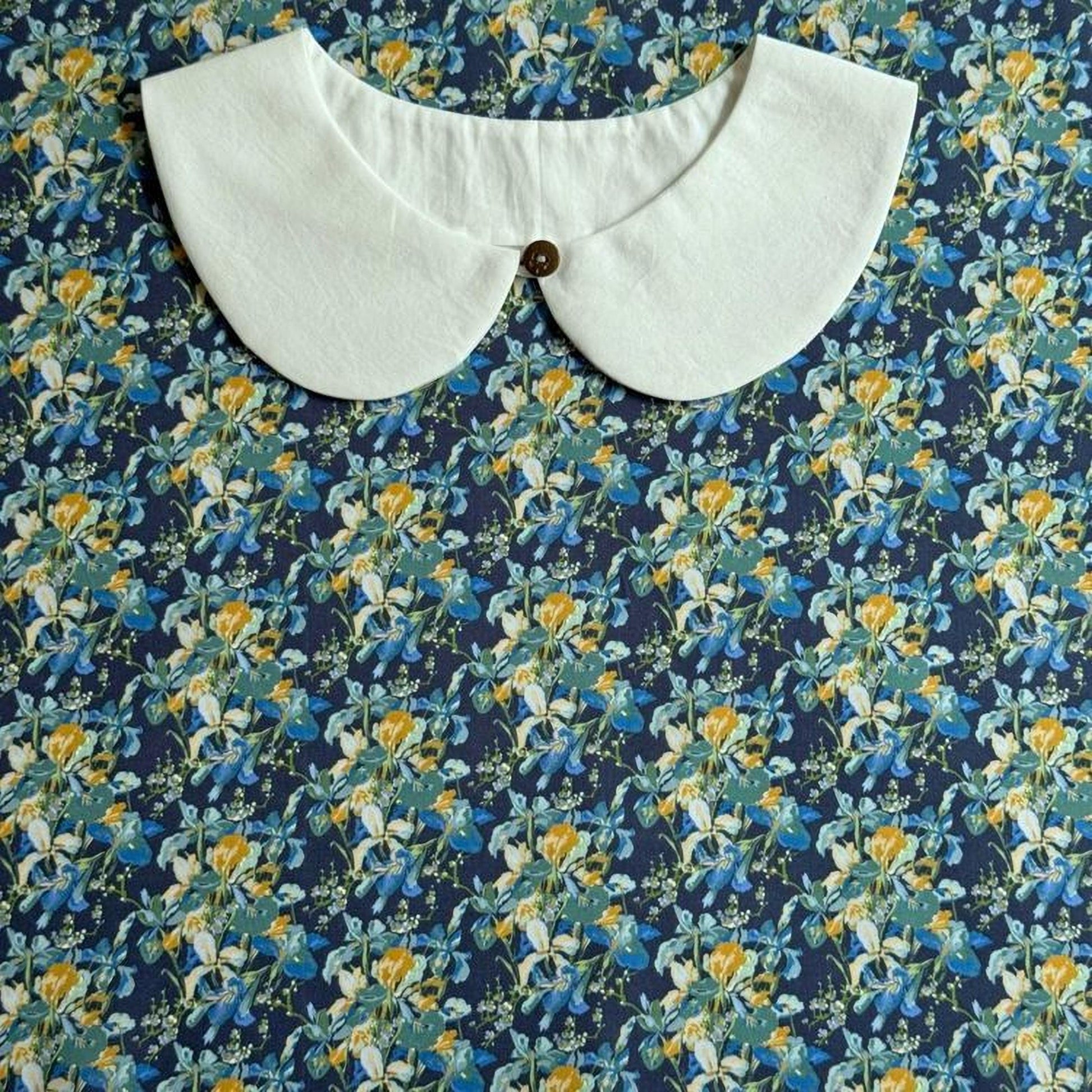 a white collar with a button, set against a background with a floral print.