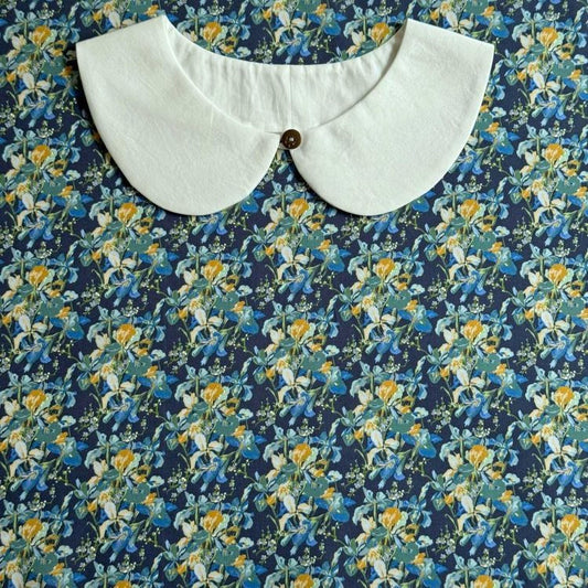 a white collar with a button, set against a background with a floral print.