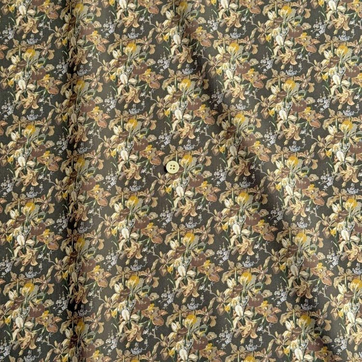 a close-up view of a fabric with a floral pattern. The fabric appears to be dark green in color, with a repeating pattern of flowers and leaves. The pattern is intricate and detailed, creating a visually appealing design. The fabric is folded and crumpled, giving it a textured appearance.