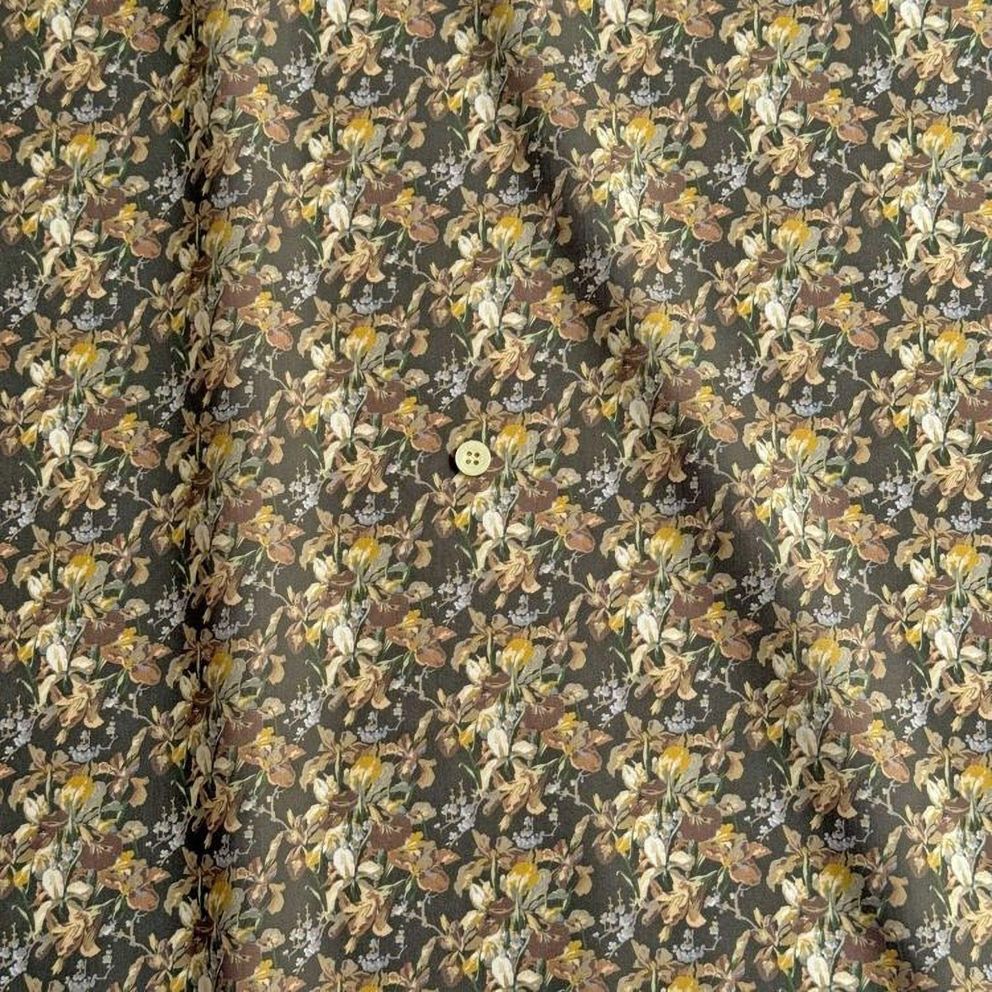 a close-up view of a fabric with a floral pattern. The fabric appears to be dark green in color, with a repeating pattern of flowers and leaves. The pattern is intricate and detailed, creating a visually appealing design. The fabric is folded and crumpled, giving it a textured appearance.