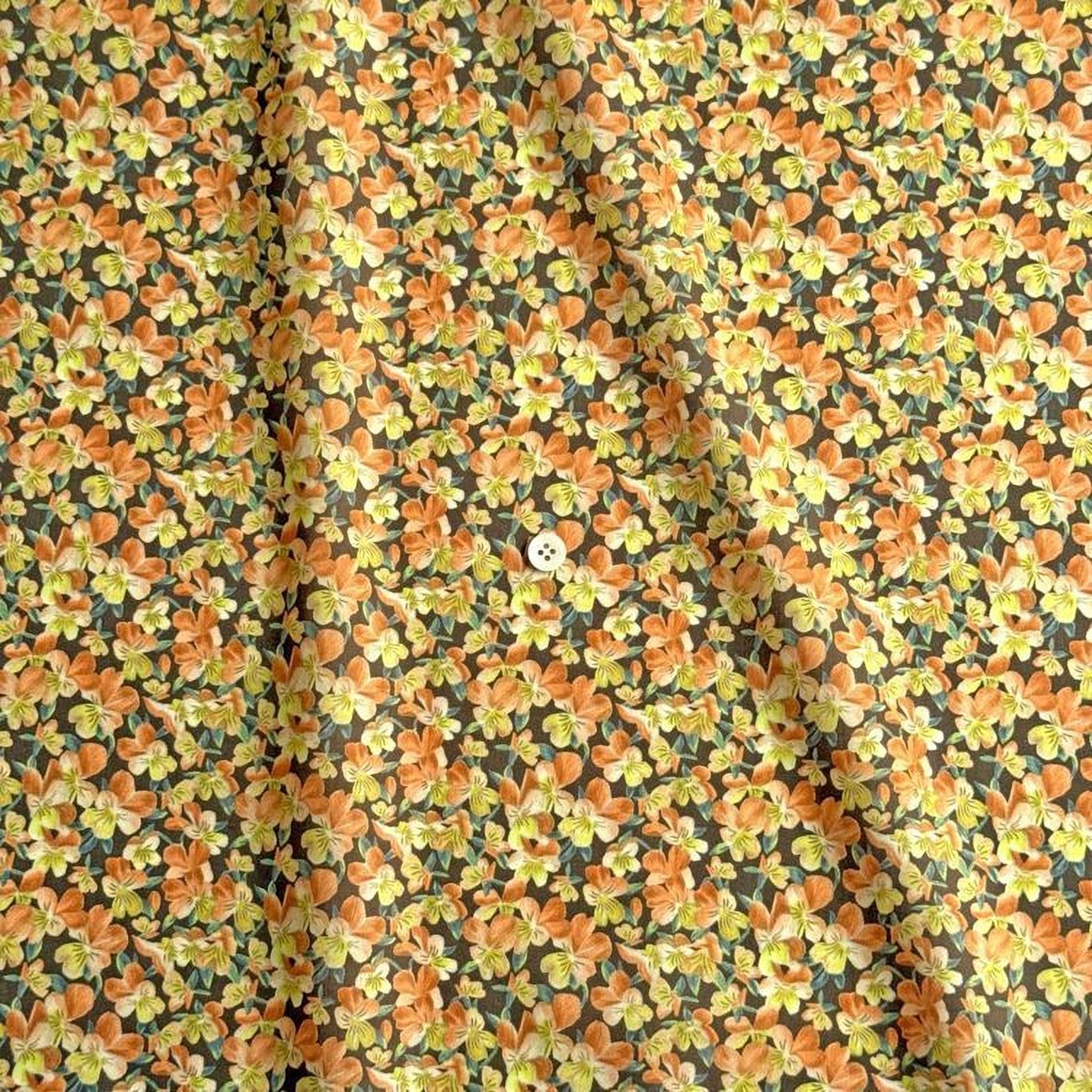 a close-up view of a fabric with a floral pattern in shades of orange and yellow. The fabric appears to be made of a soft, textured material, and there is a small white button visible in the center of the pattern.